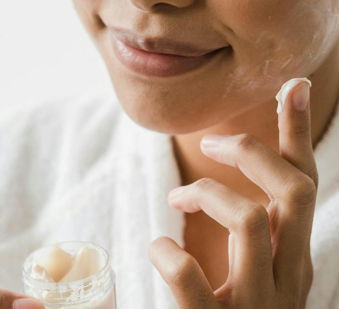 Femme s'hydrate le visage avec de la crème hydratante.