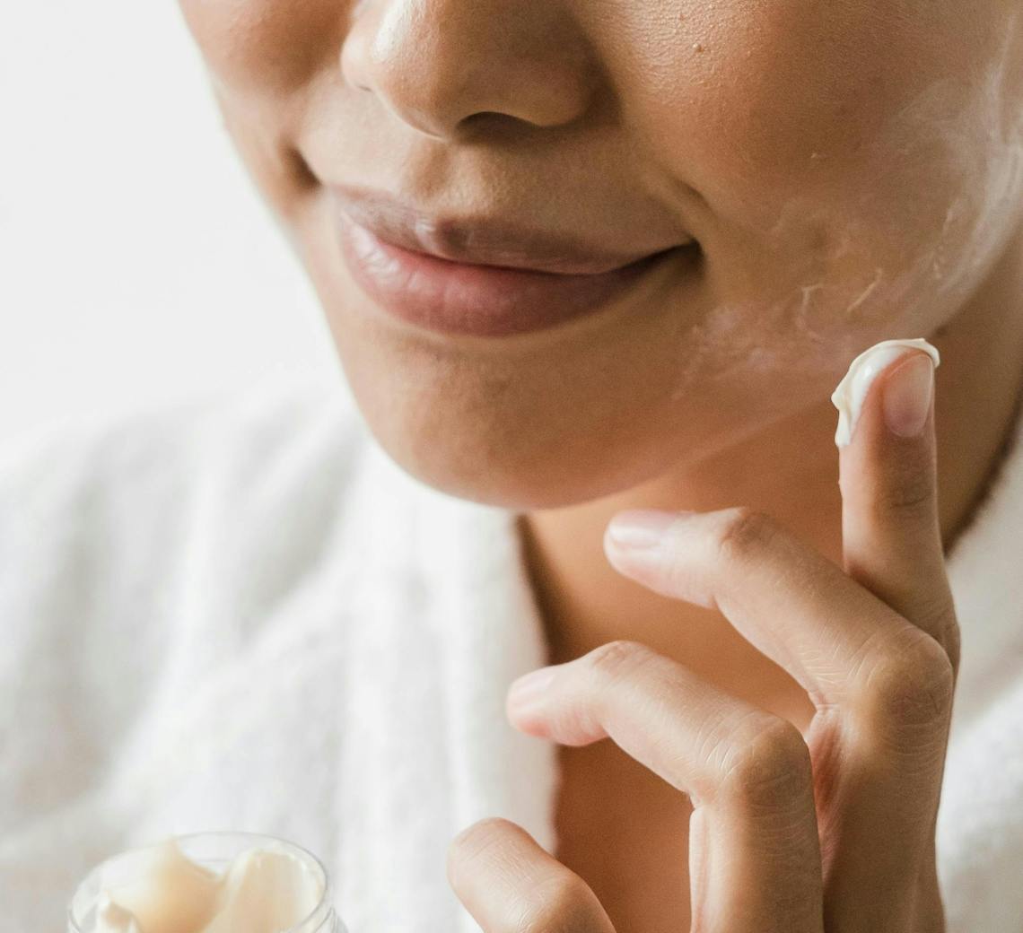 Femme s'hydrate le visage avec de la crème hydratante.