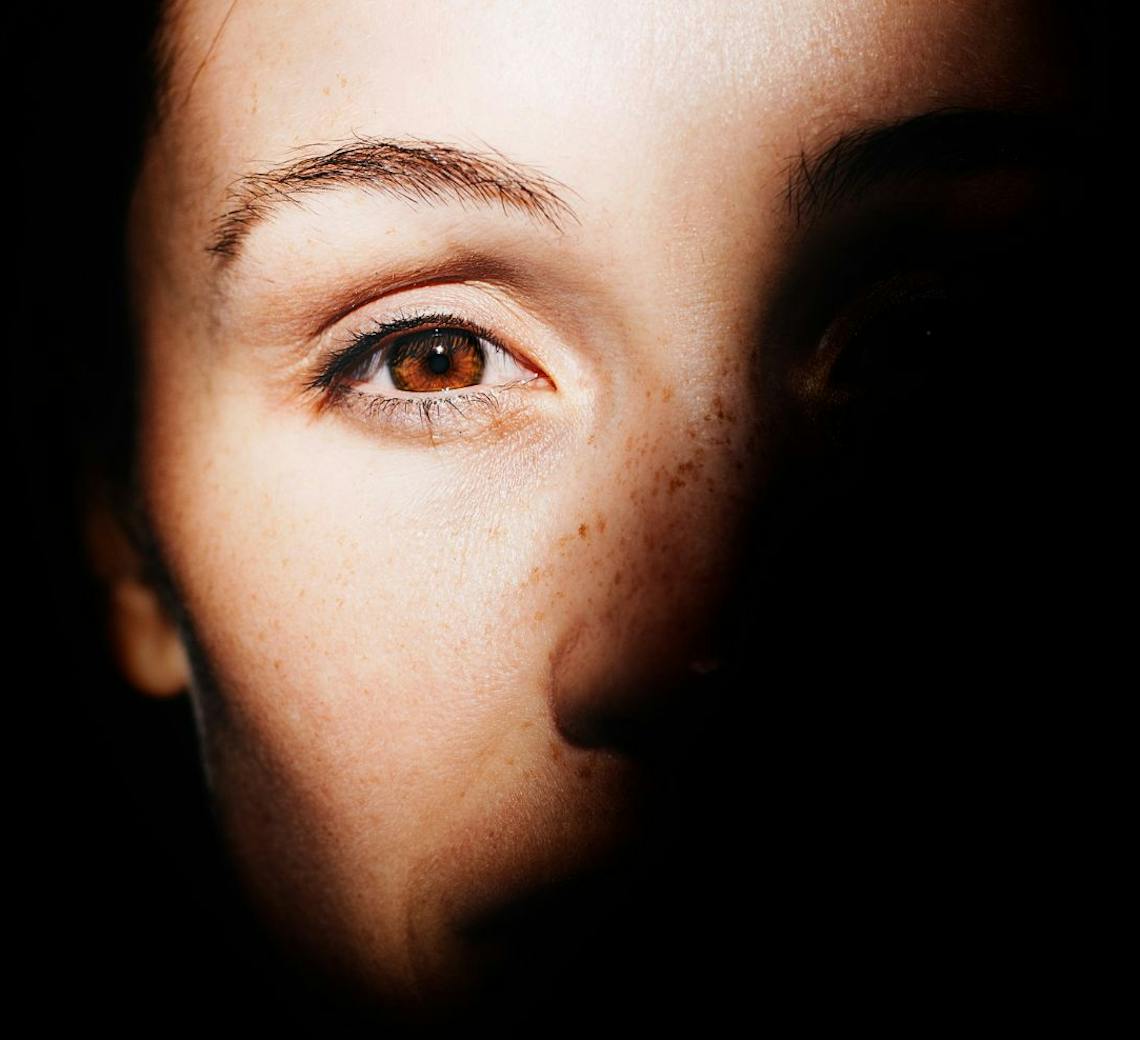 Visage d'une jeune femme dans l'ombre.