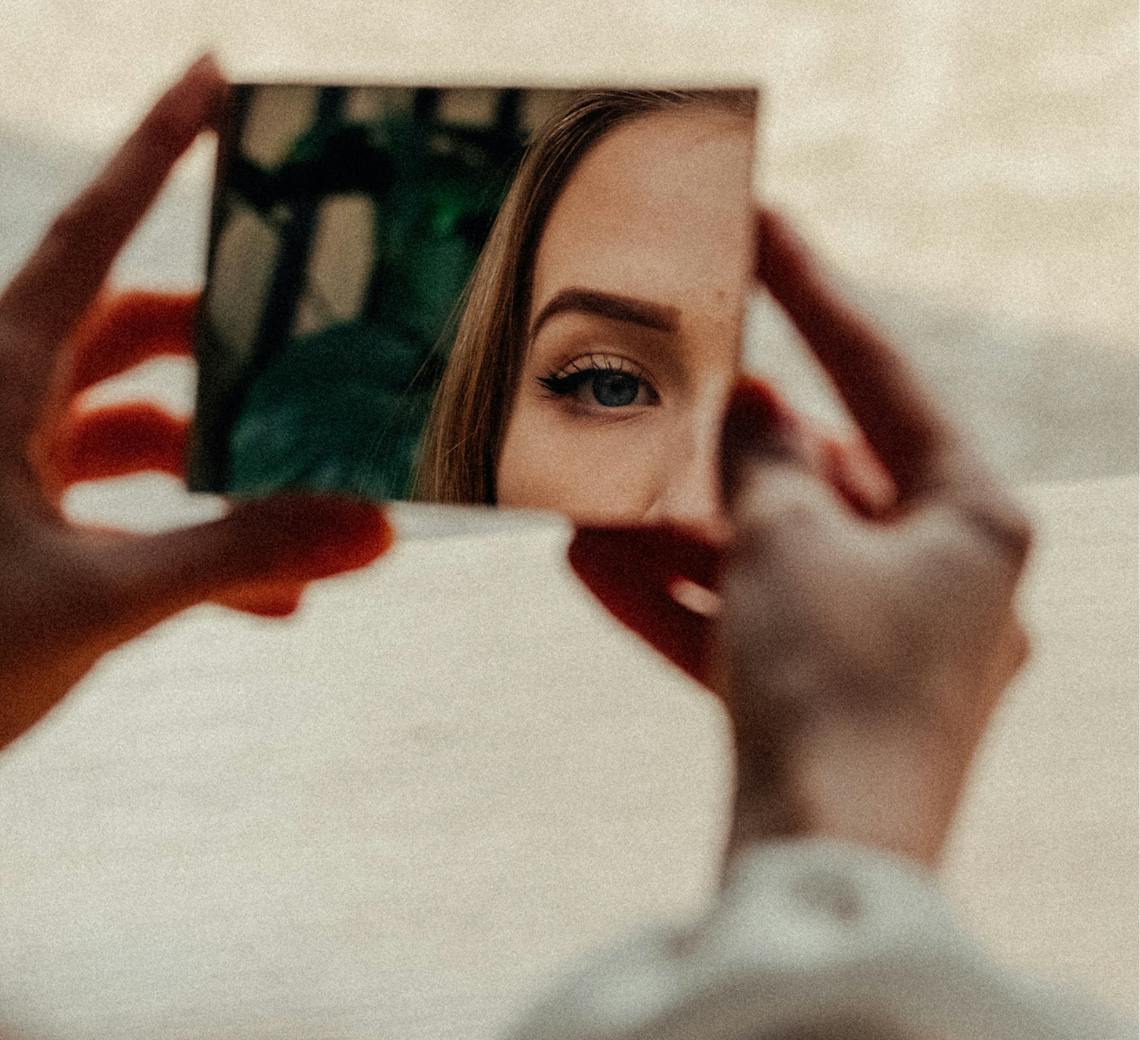 Femme qui regarde son visage dans le miroir.