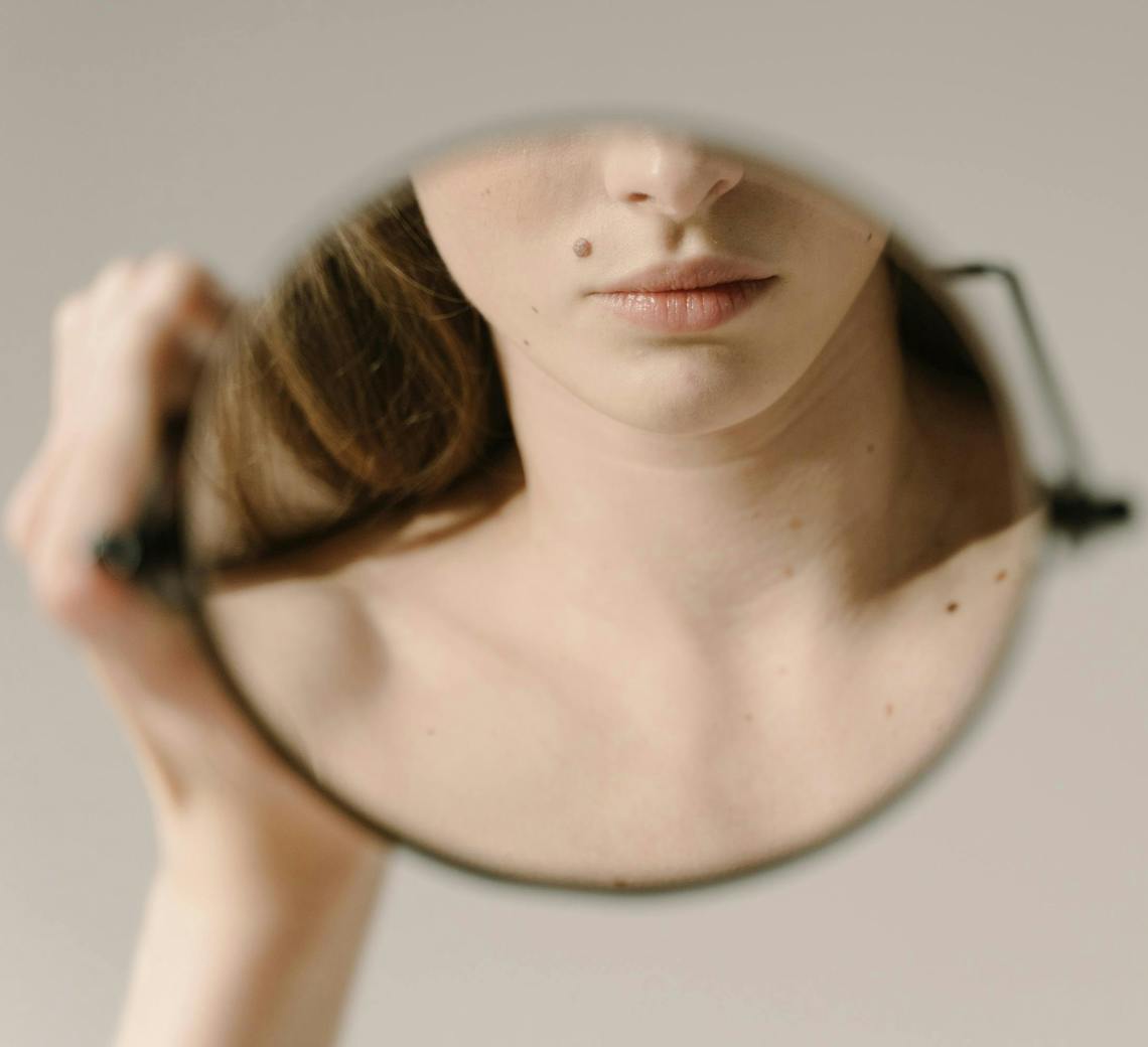 Jeune femme qui se regarde dans le miroir.