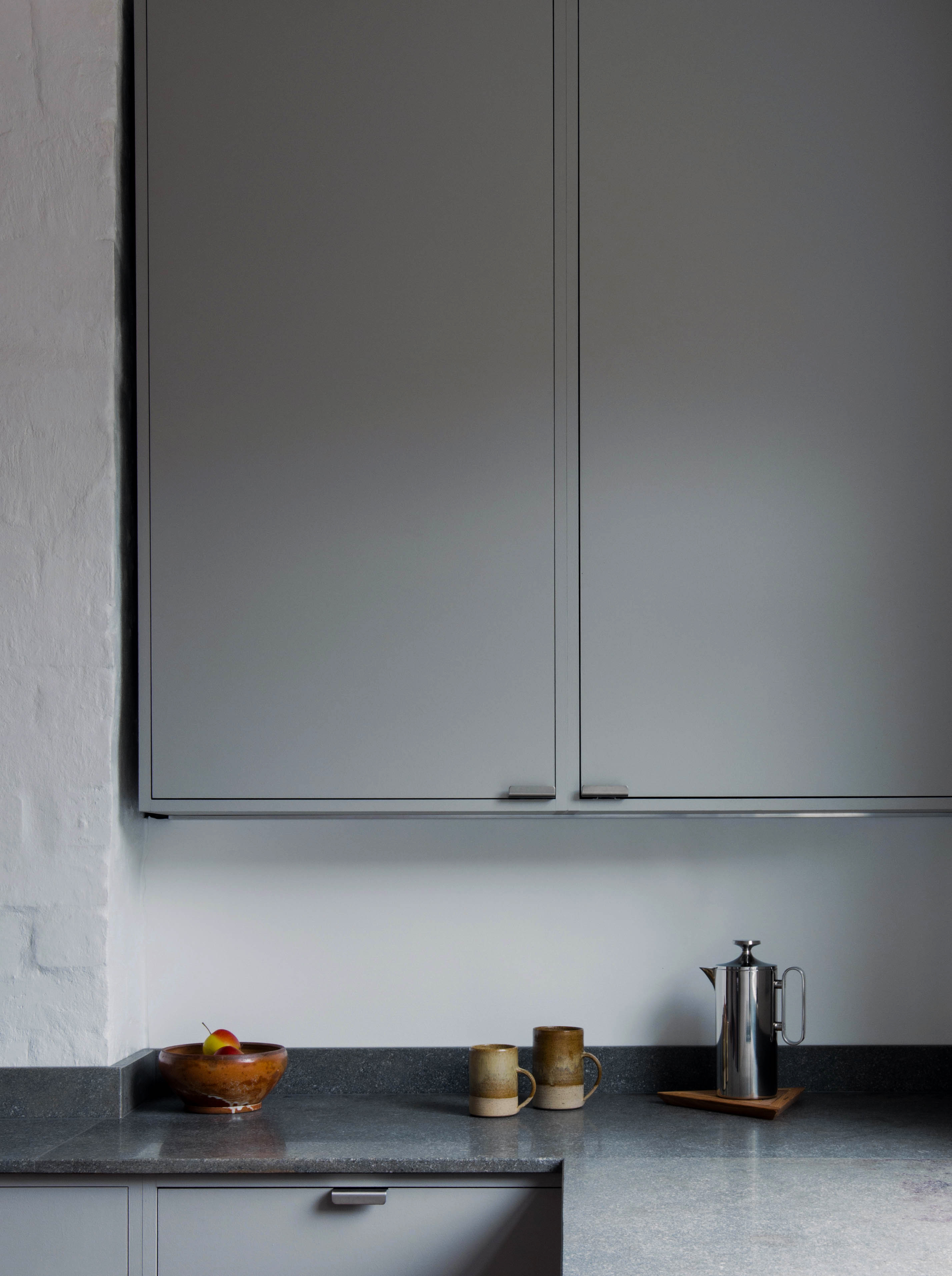 Minimal warm grey painted Ma-kon kitchen with limestone worktops.