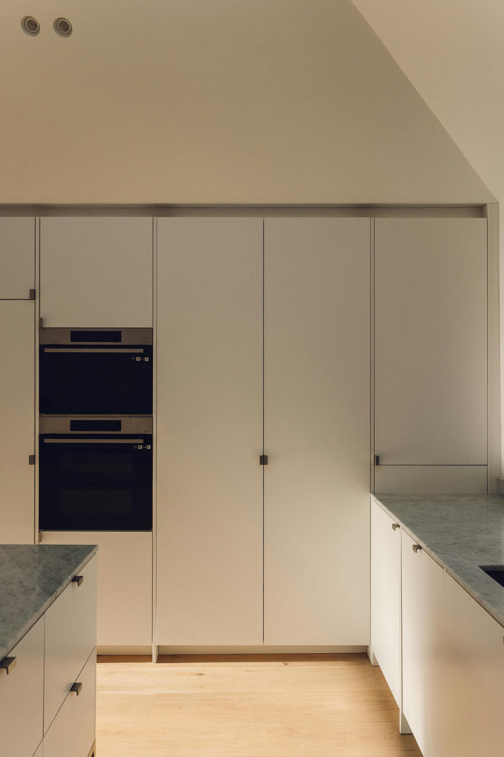 Minimal white painted Ma-kon kitchen with Carrara marble worktop.