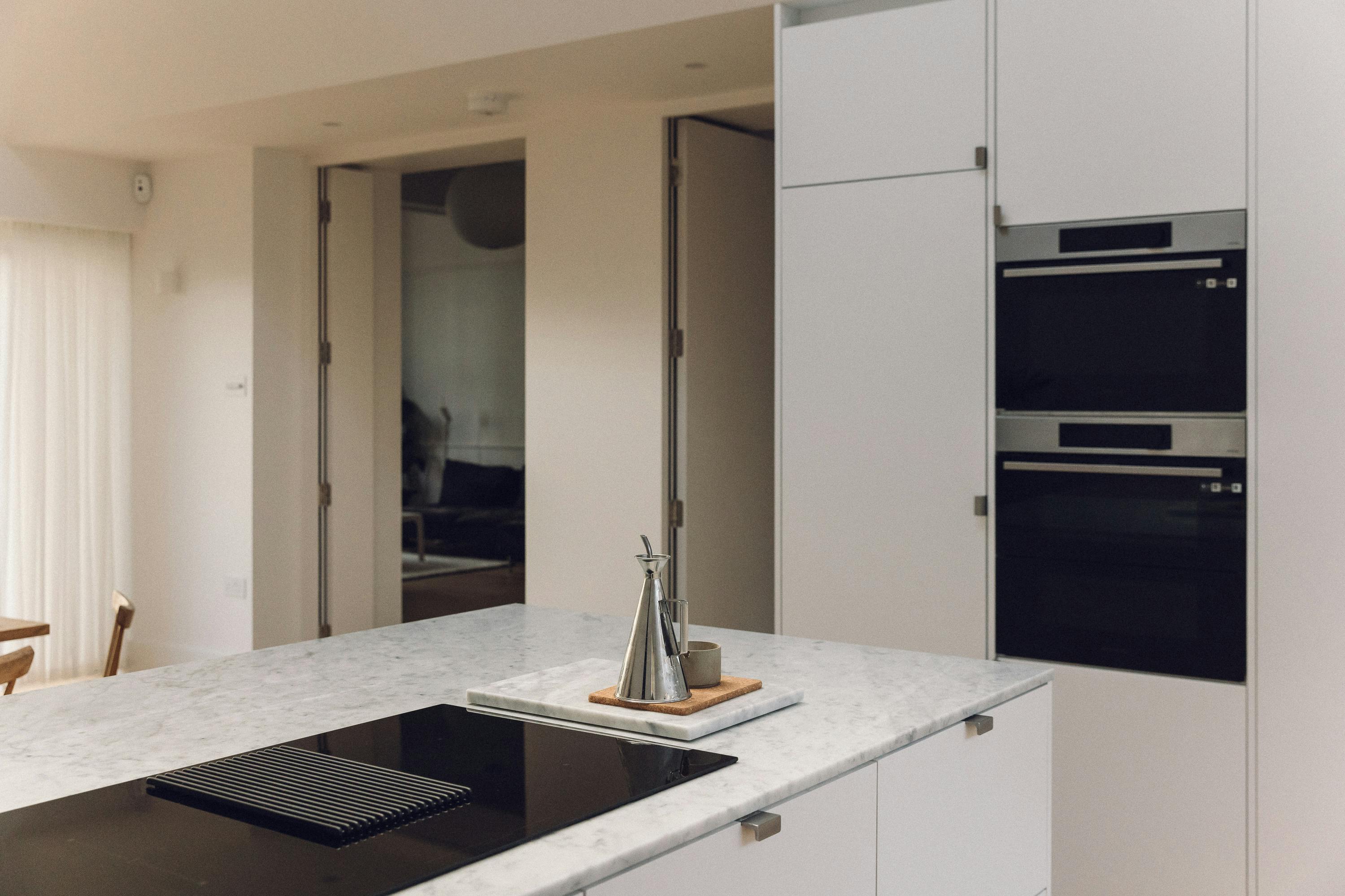 Minimal white painted Ma-kon kitchen with Carrara marble worktop.