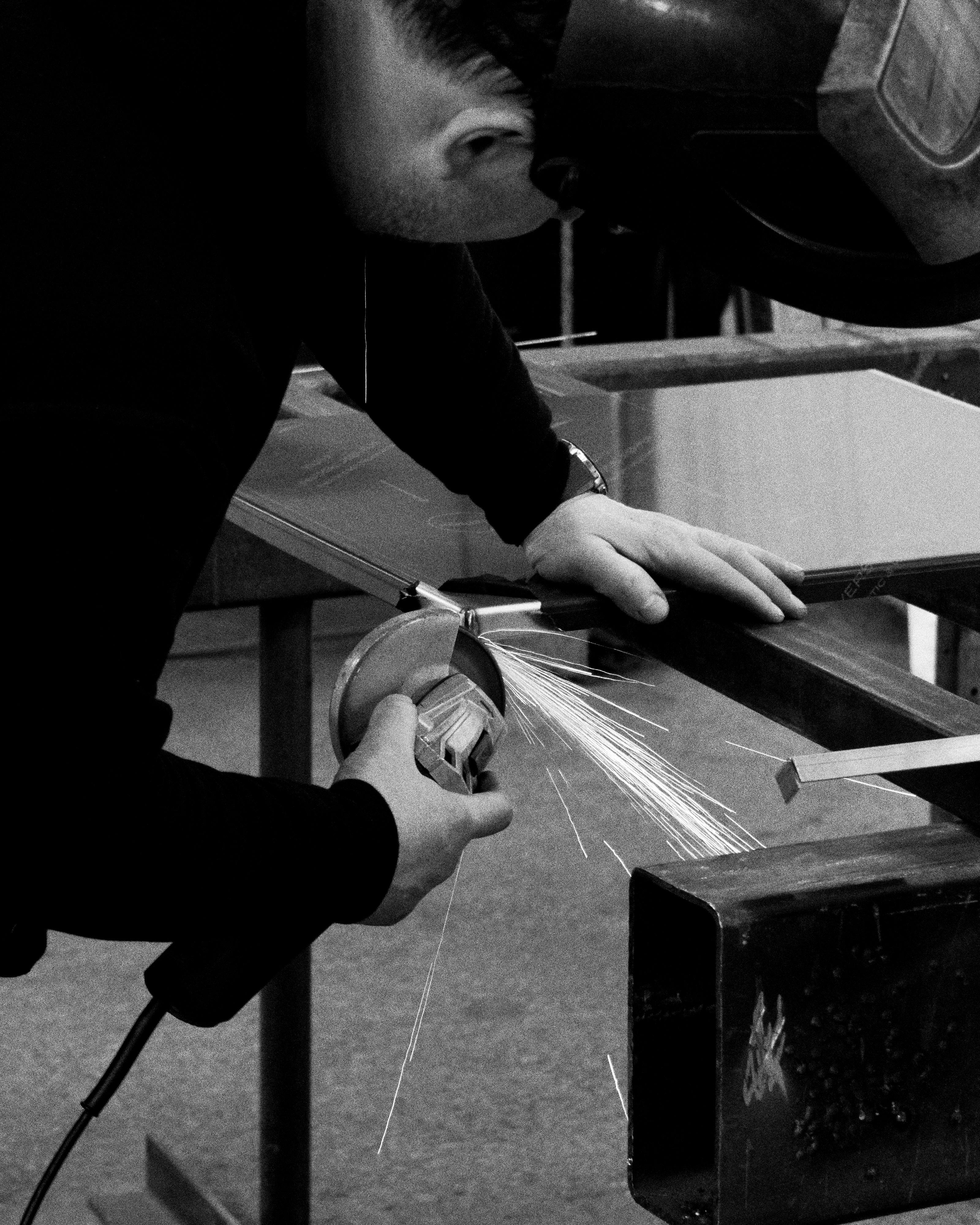 Black and white photo fabricating a stainless steel Ma-kon kitchen.