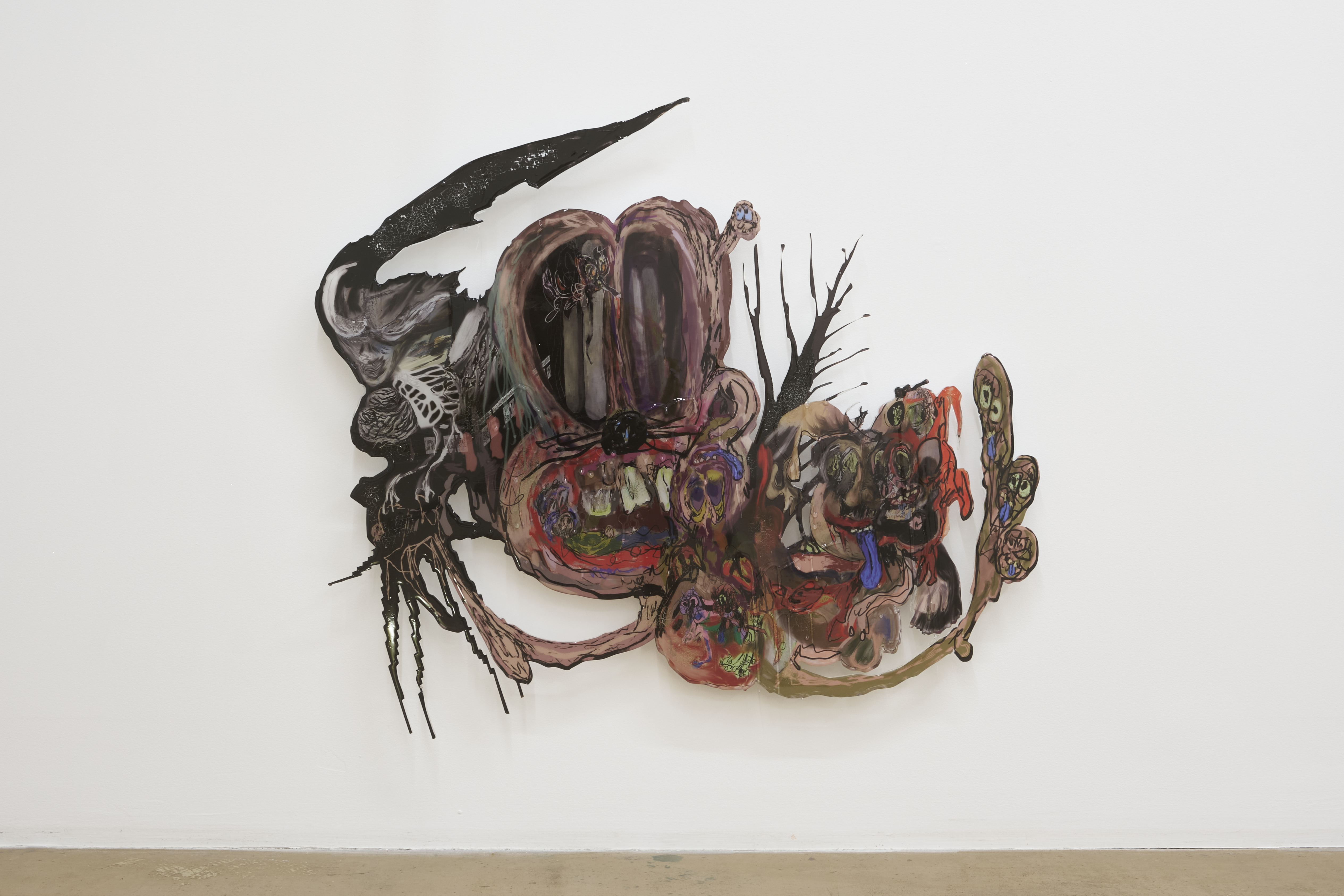 Fotogrāfijā attēlots abstrakts, daudzkrāsains sienas objekts ar multfilmu vai komiksu varoņu iezīmēm un deformētām formām.