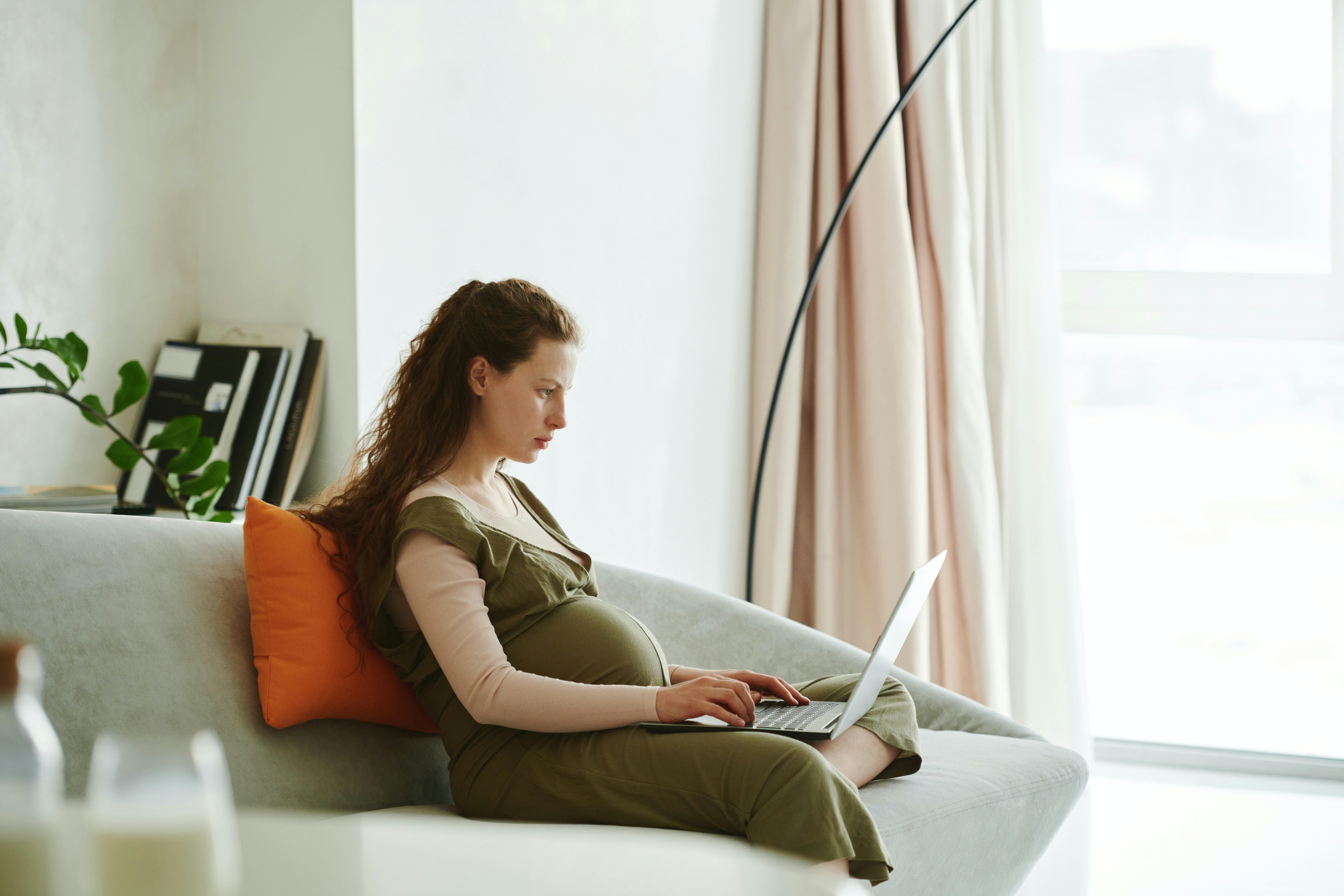 Woman sitting on a couch typing on her laptop. 