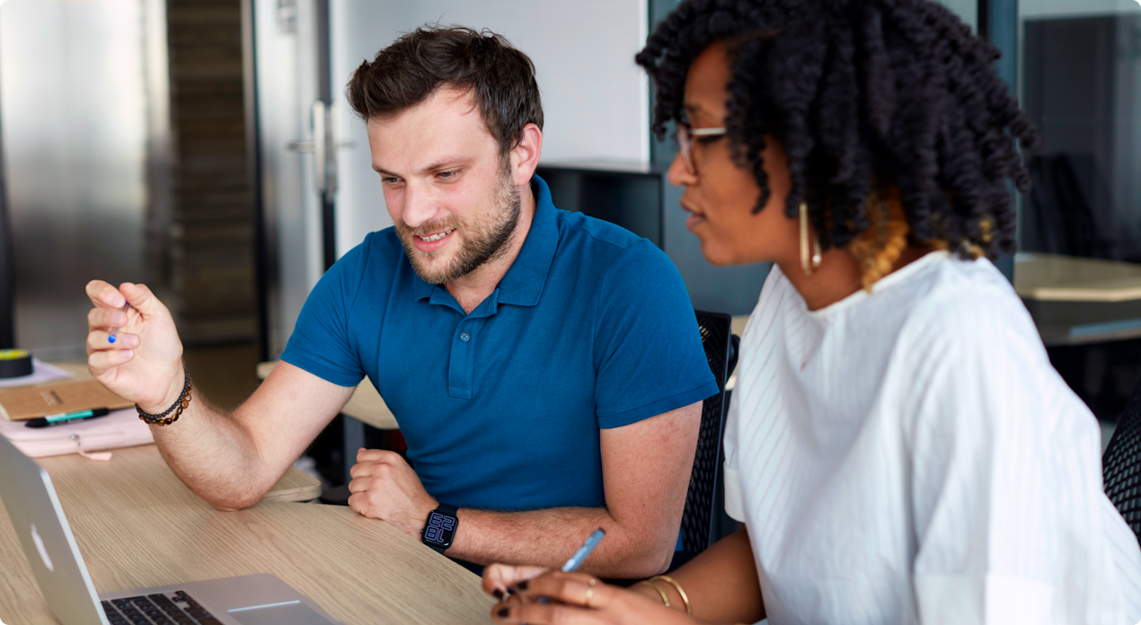 two people talking in front of a laptop