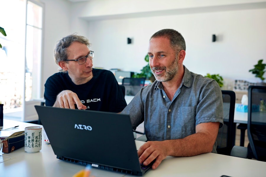 deux hommes discutant devant un laptop
