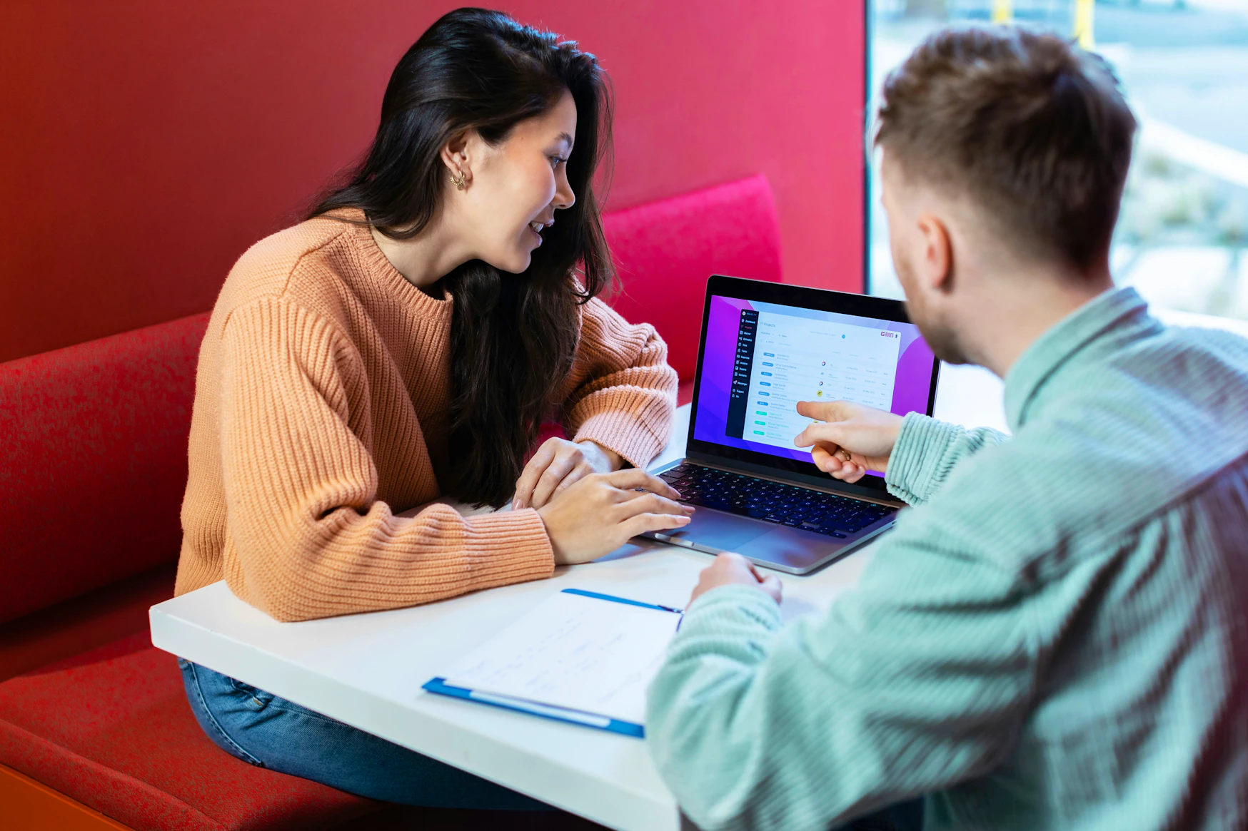Freelancer Mentoring: Ein Freelancer erklärt einer anderen Freelancerin etwas und zeigt auf den Laptop.