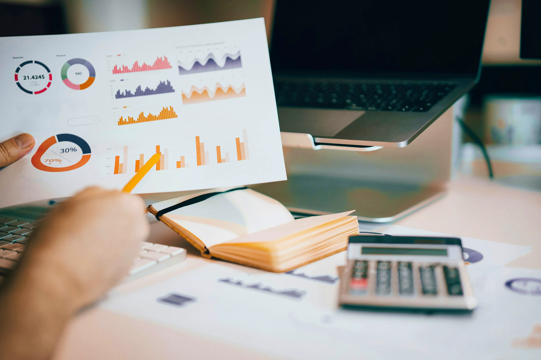 Un graphique composé de différents schémas est présenté. En arrière-plan, un ordinateur portable, une calculatrice et d'autres documents du rapport.