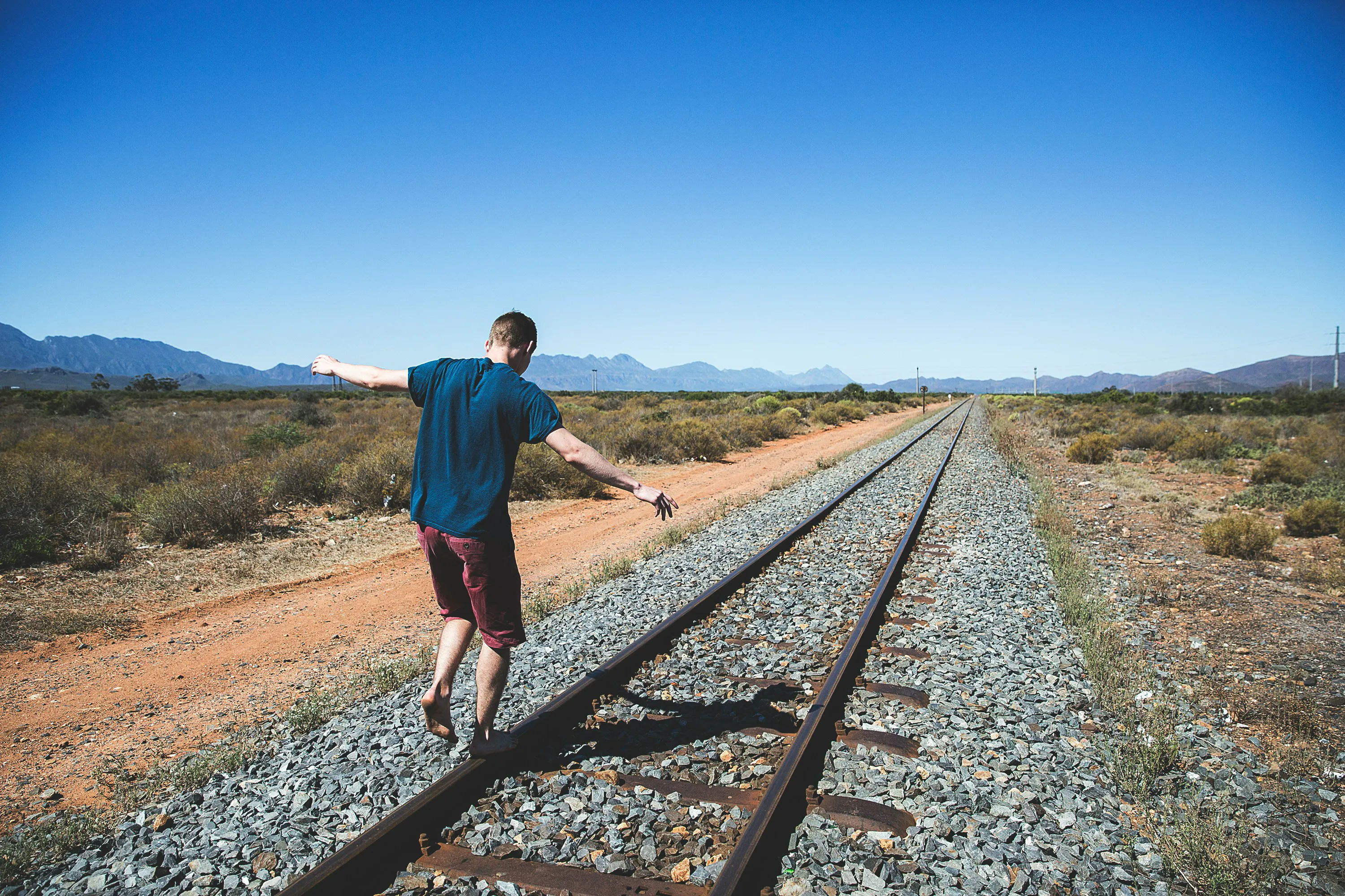 Person walking on train track rails - Photo by Joshua Earle on Unsplash