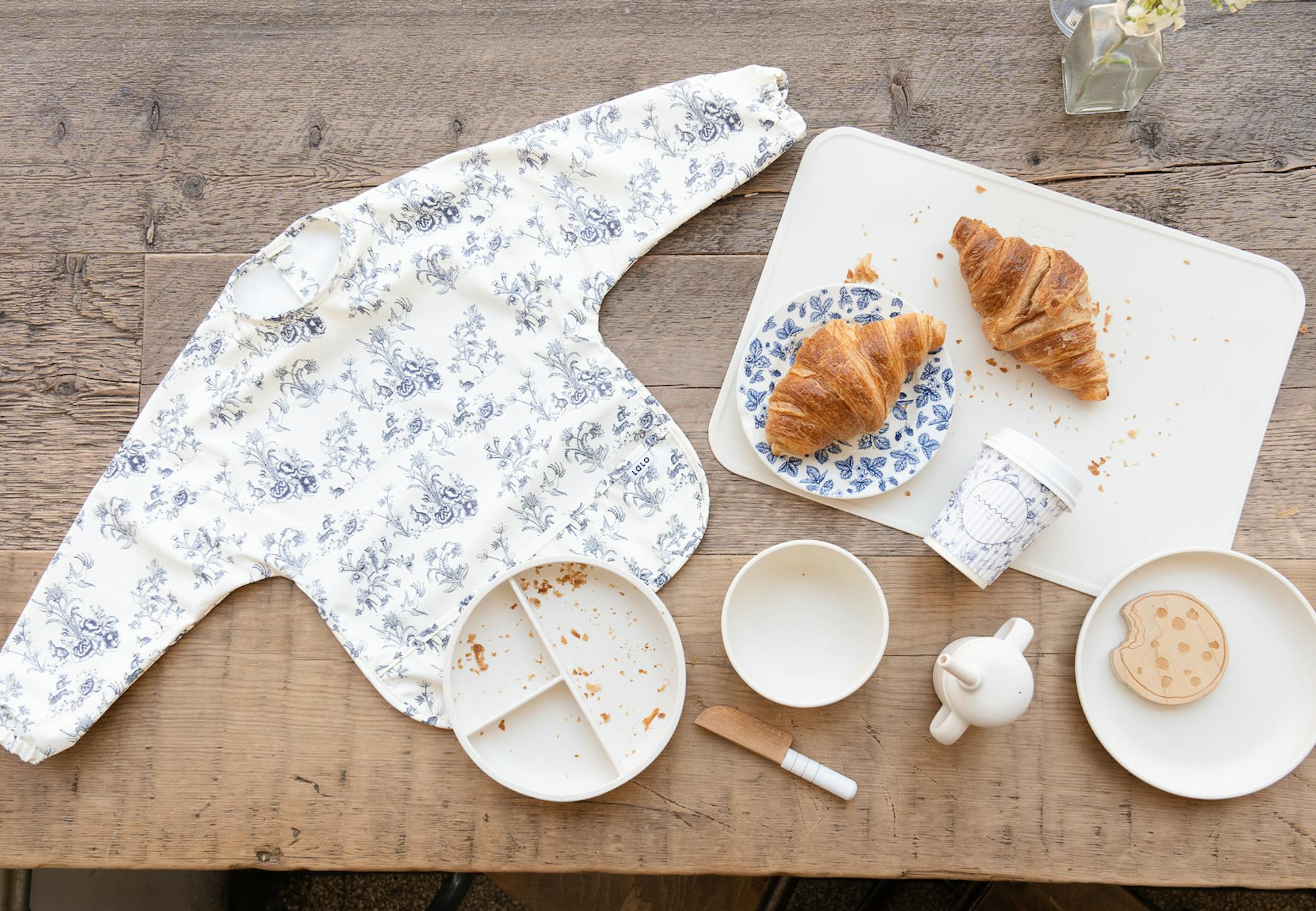 flat lay of lalo bib, croissants, and lalo accessories