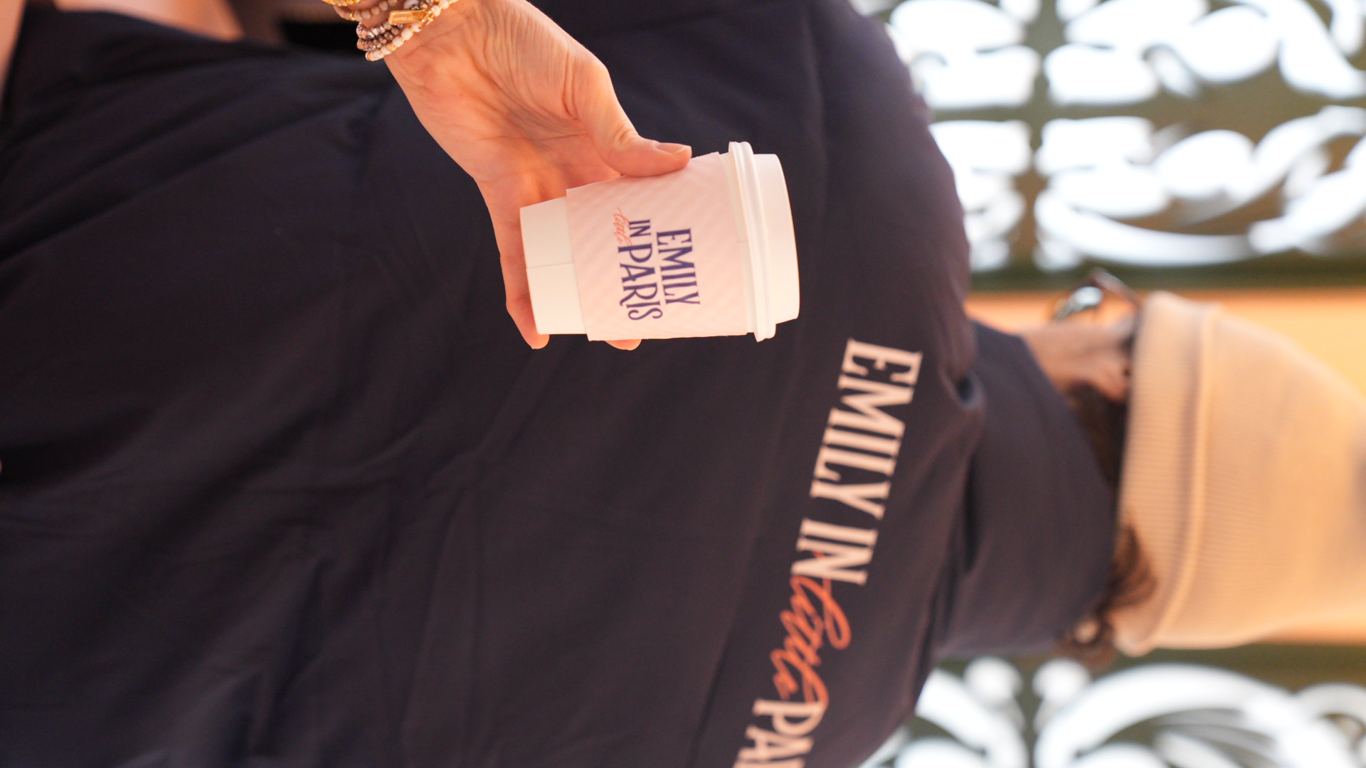 woman holding up emily in little paris branded cup as man pours a hot cocoa