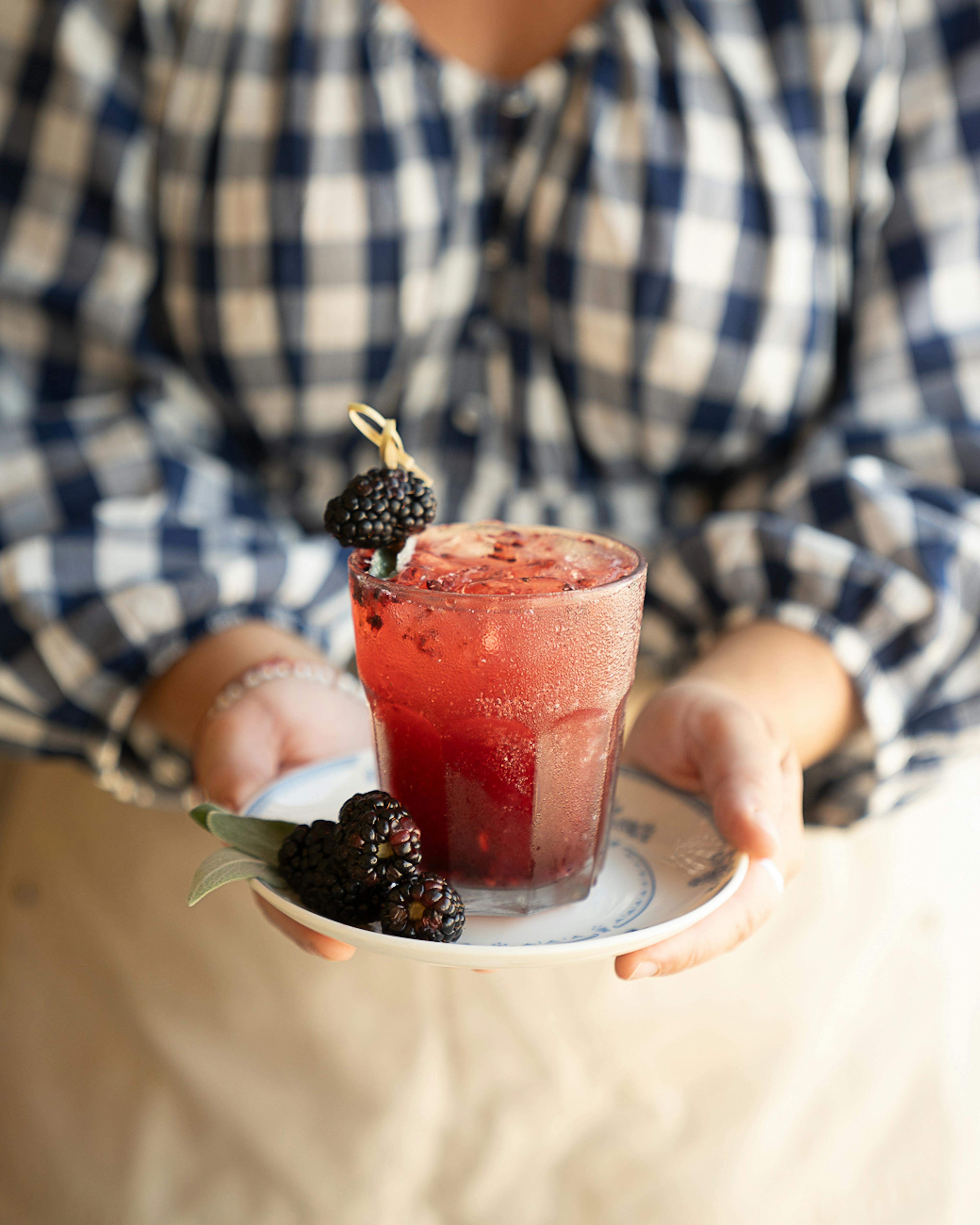 woman holding blackberry sage smash cocktial