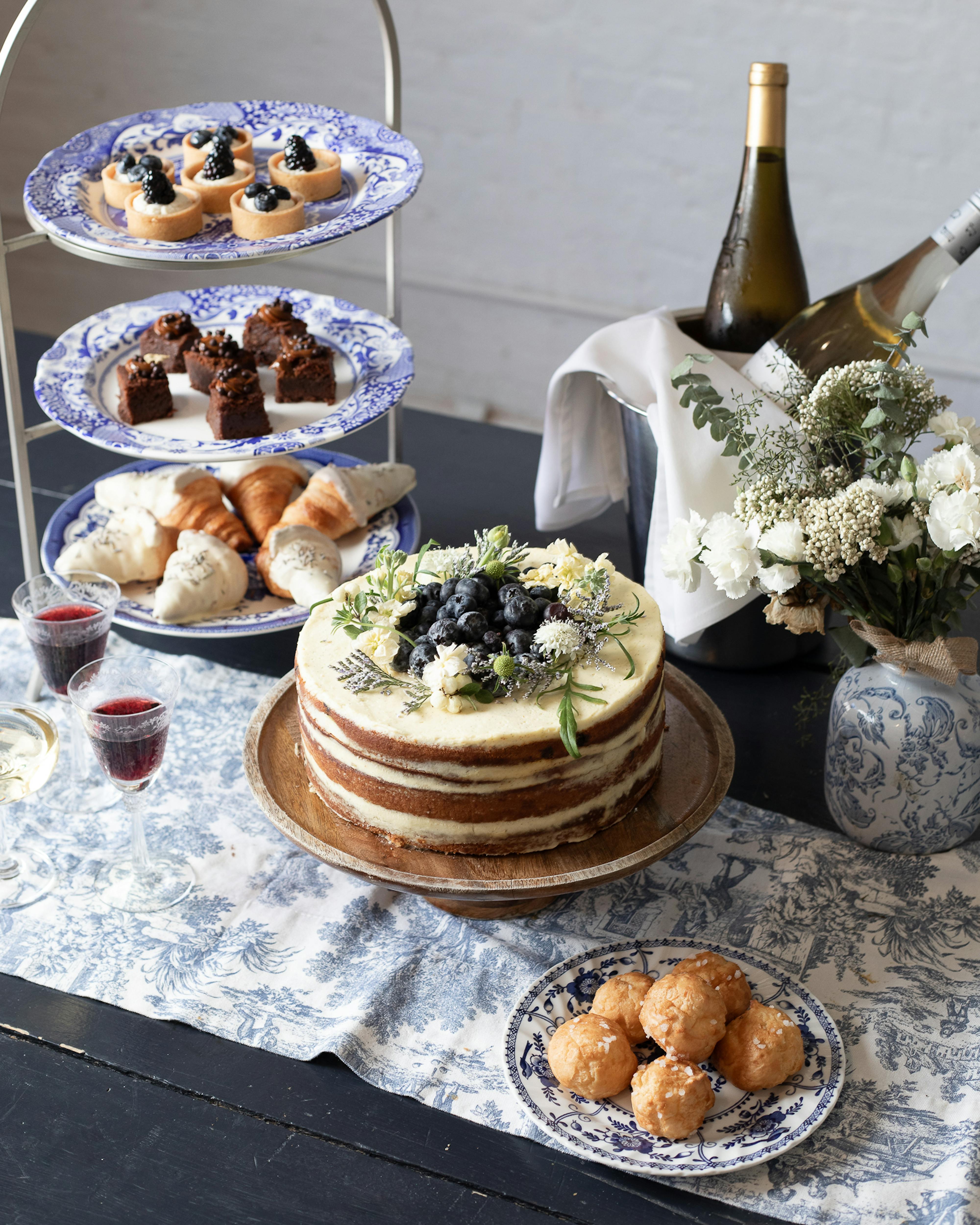 tiered stands with sweets and cake and wine on table