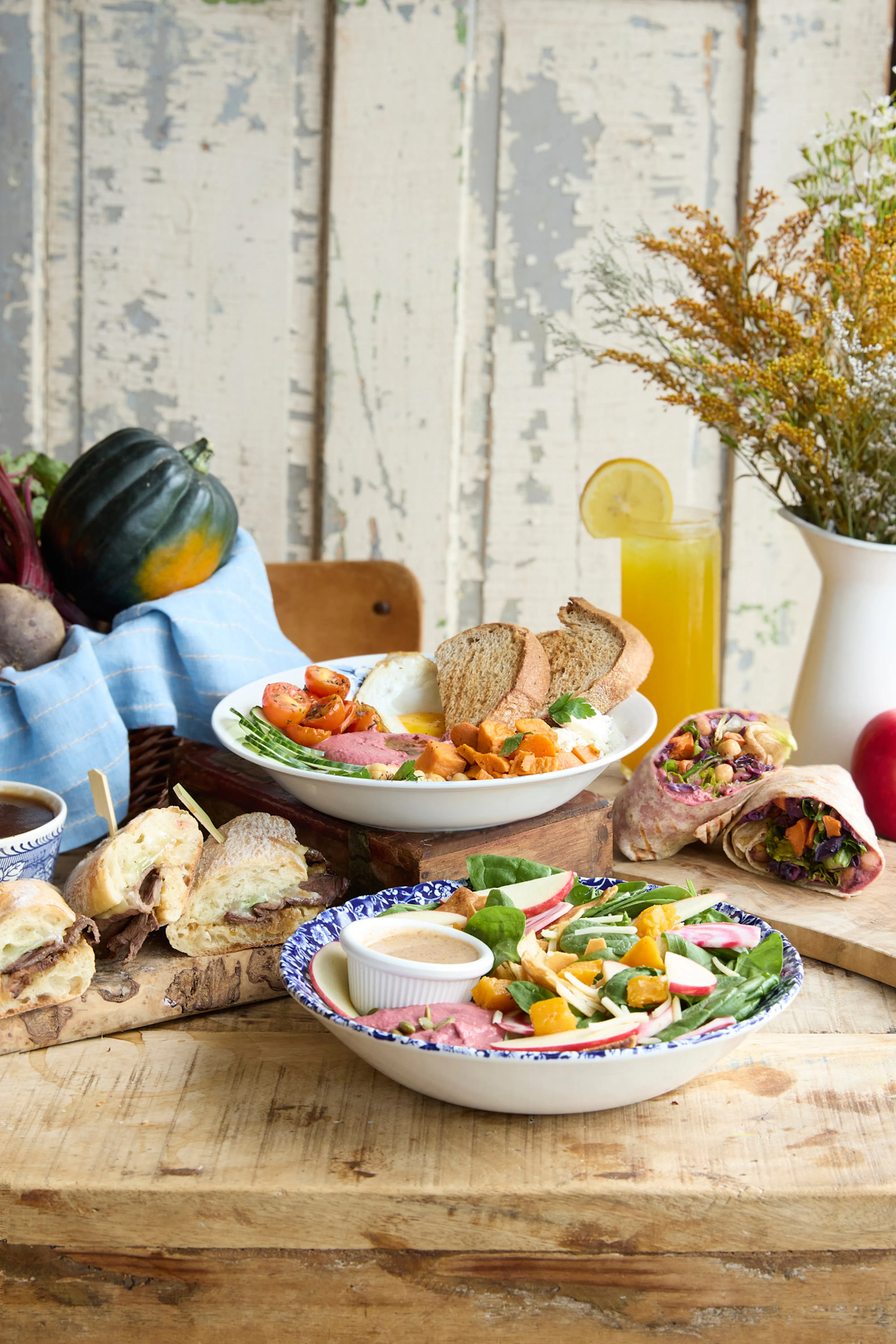 fall menu spread on wooden table with sandwiches & salads