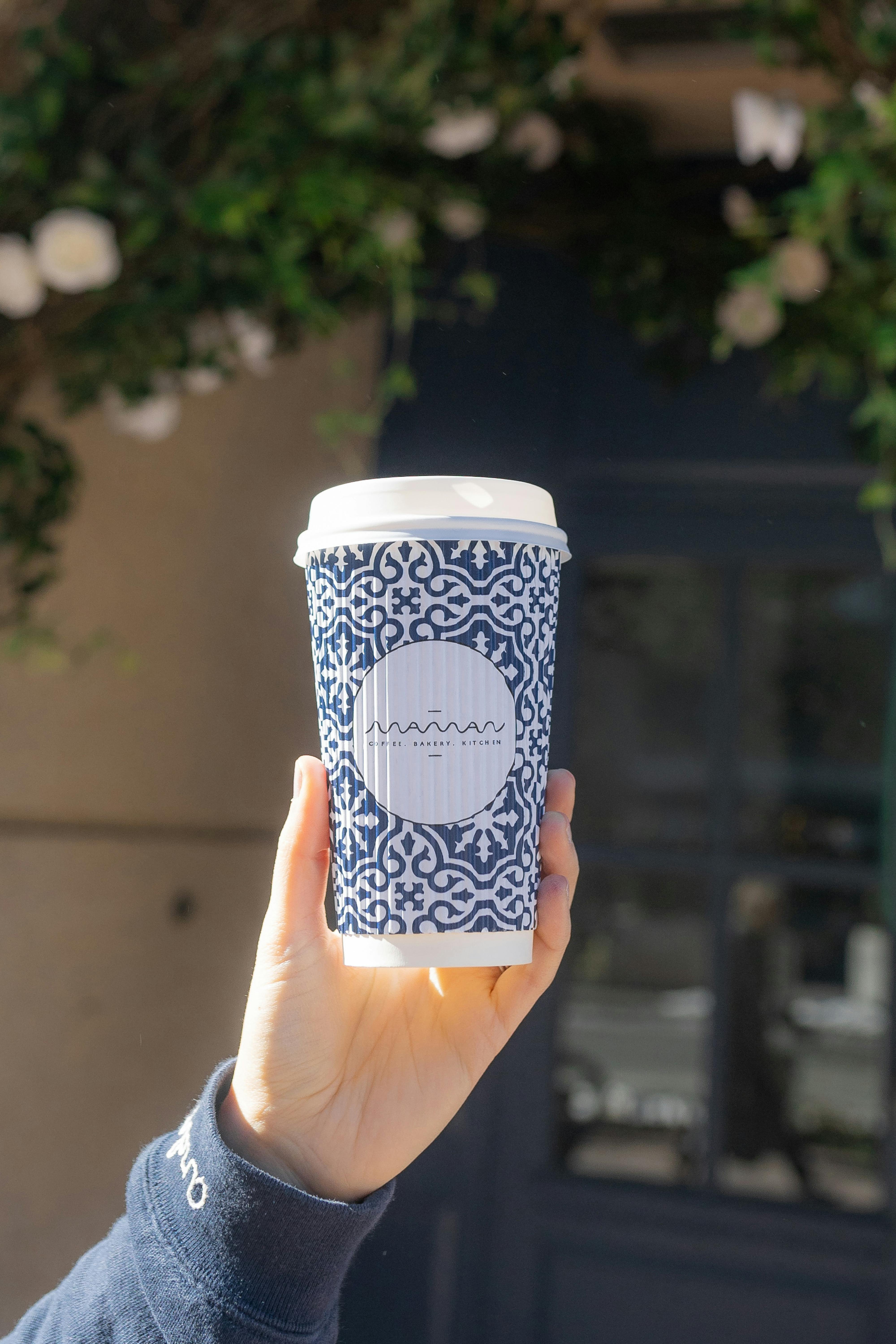 hand holding coffee cup in front of store