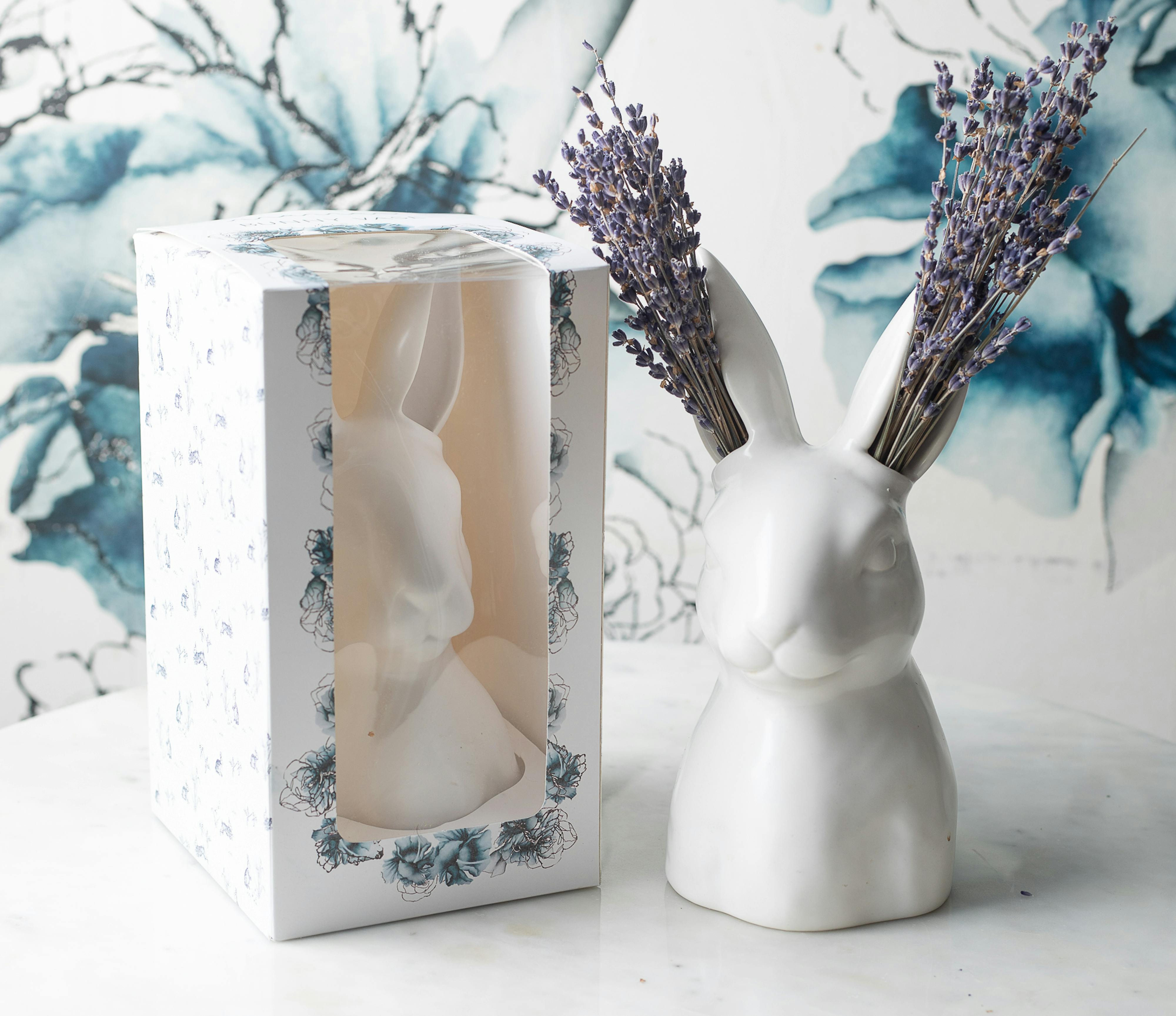 a bunny shaped vase on a marble table with it's blue and white packaging
