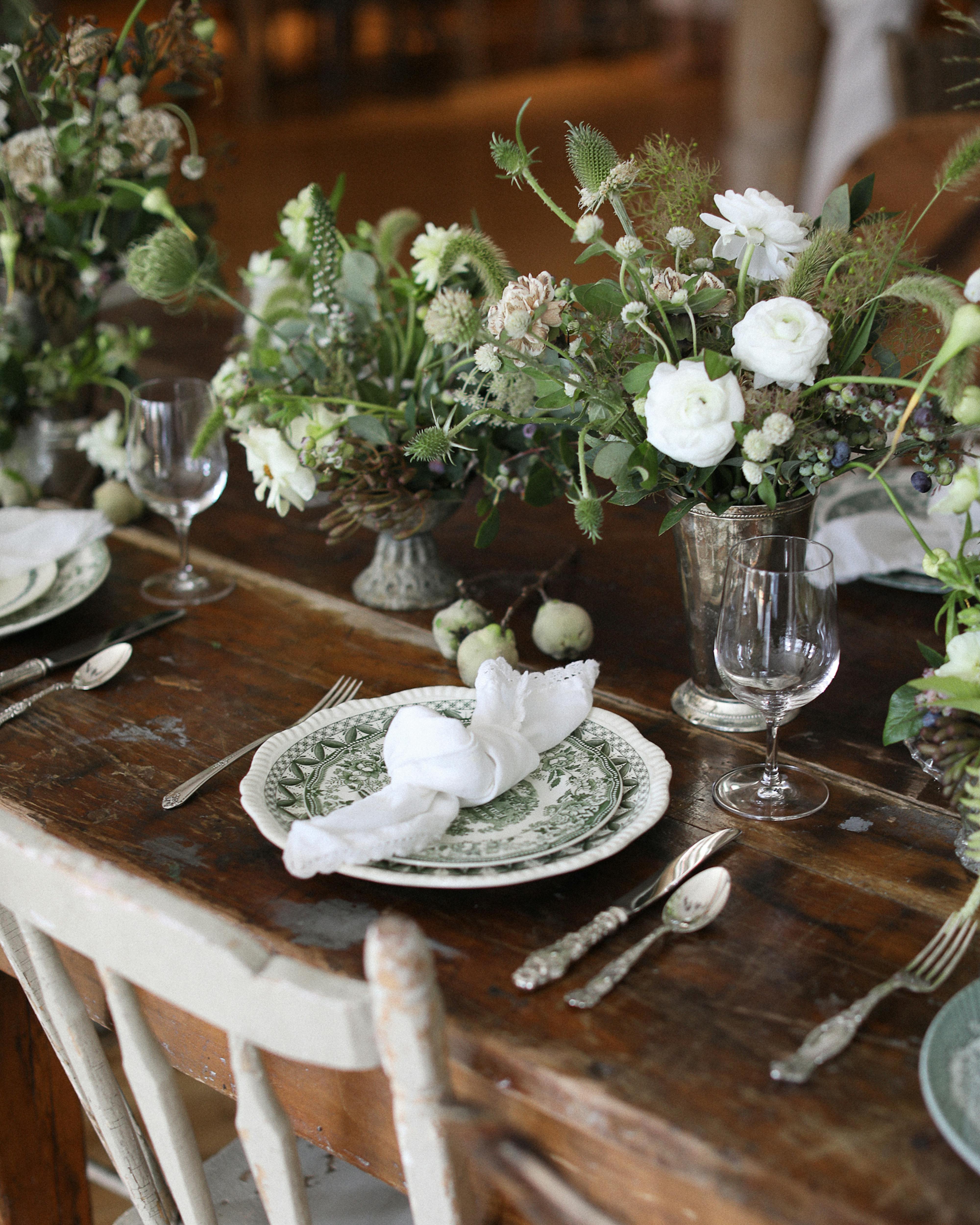 rustic place setting on table with green and white plates, florals, and vintage cutlery