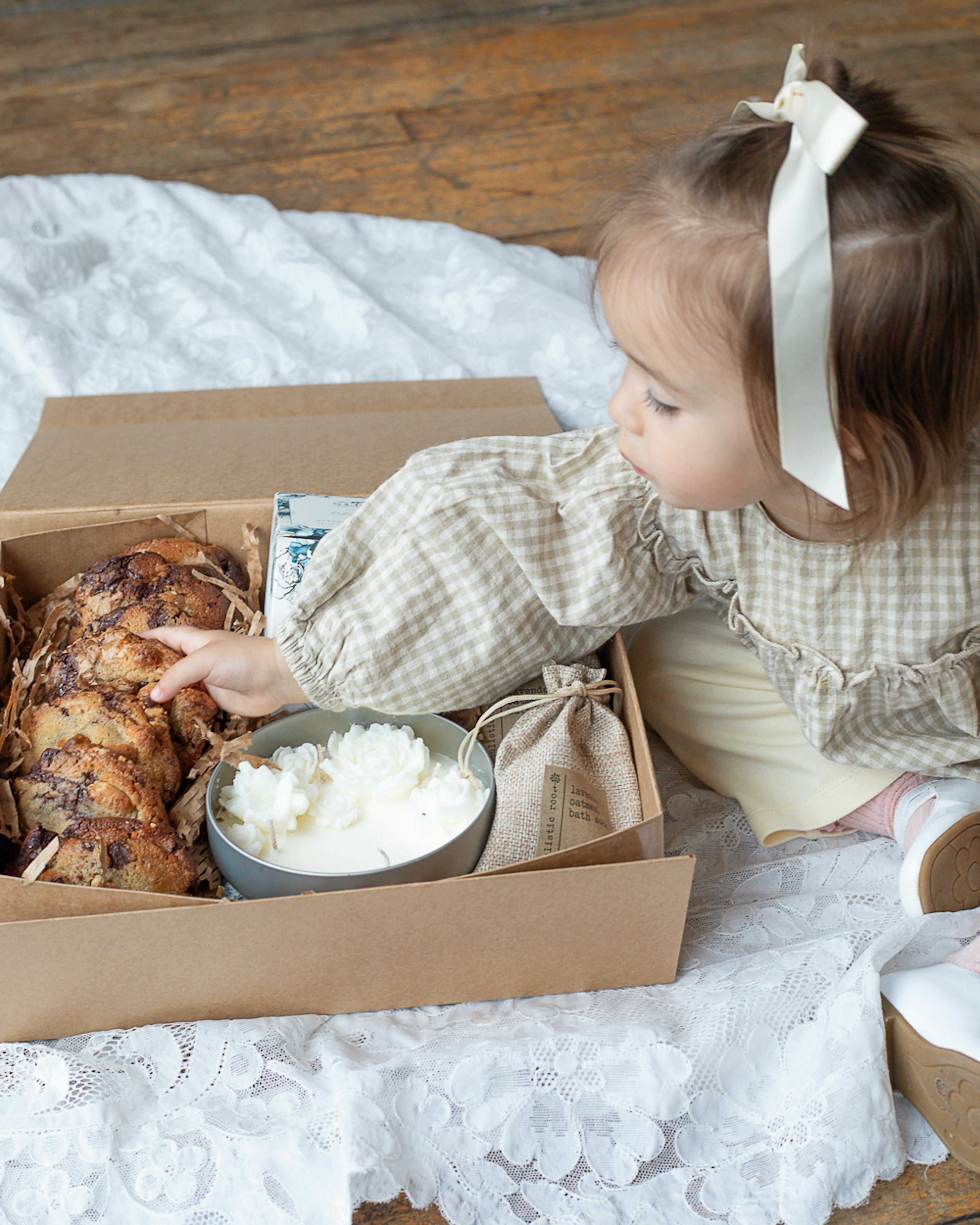 little girl reaching for cookie in gift box