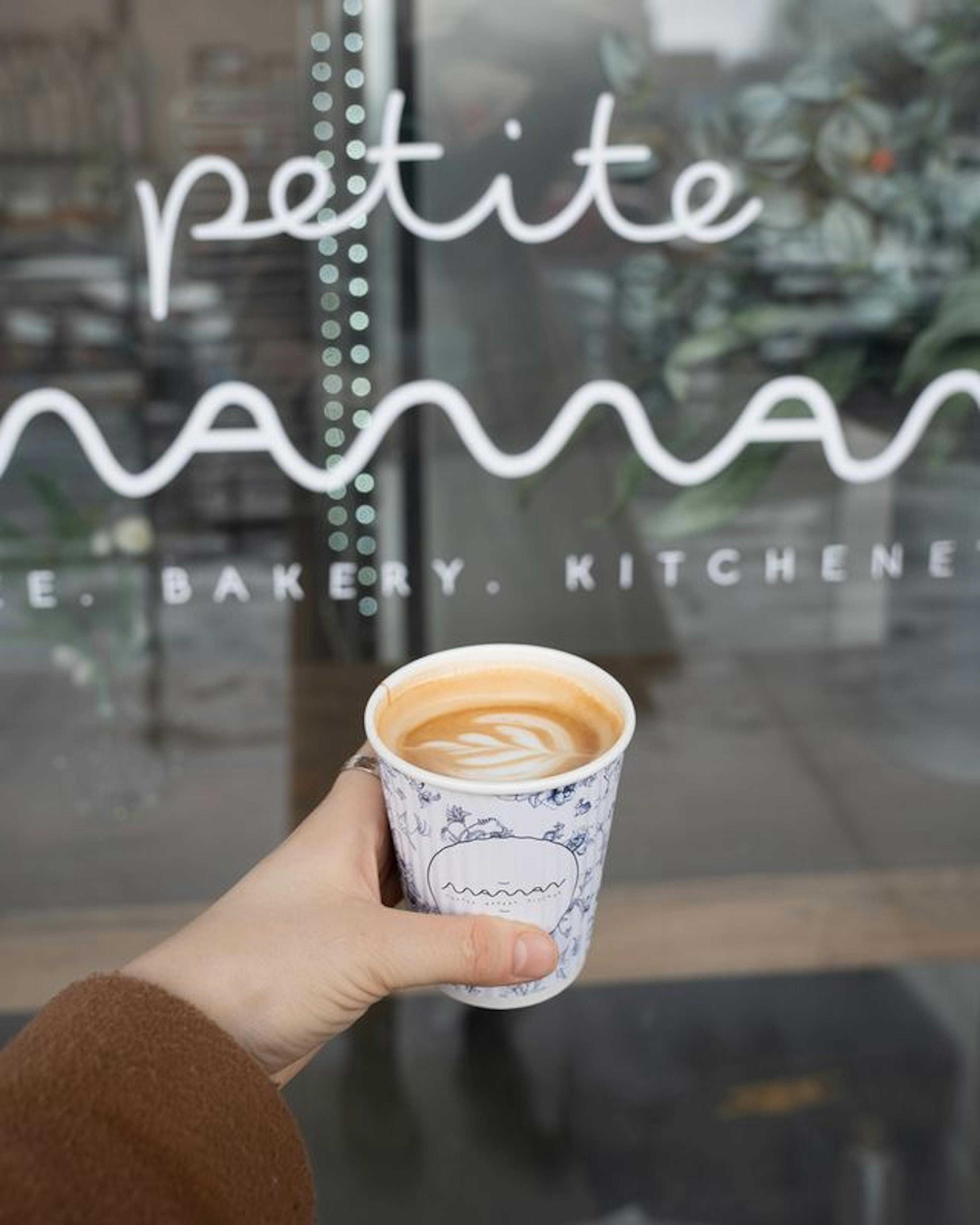 hand holding coffee cup with sign in background