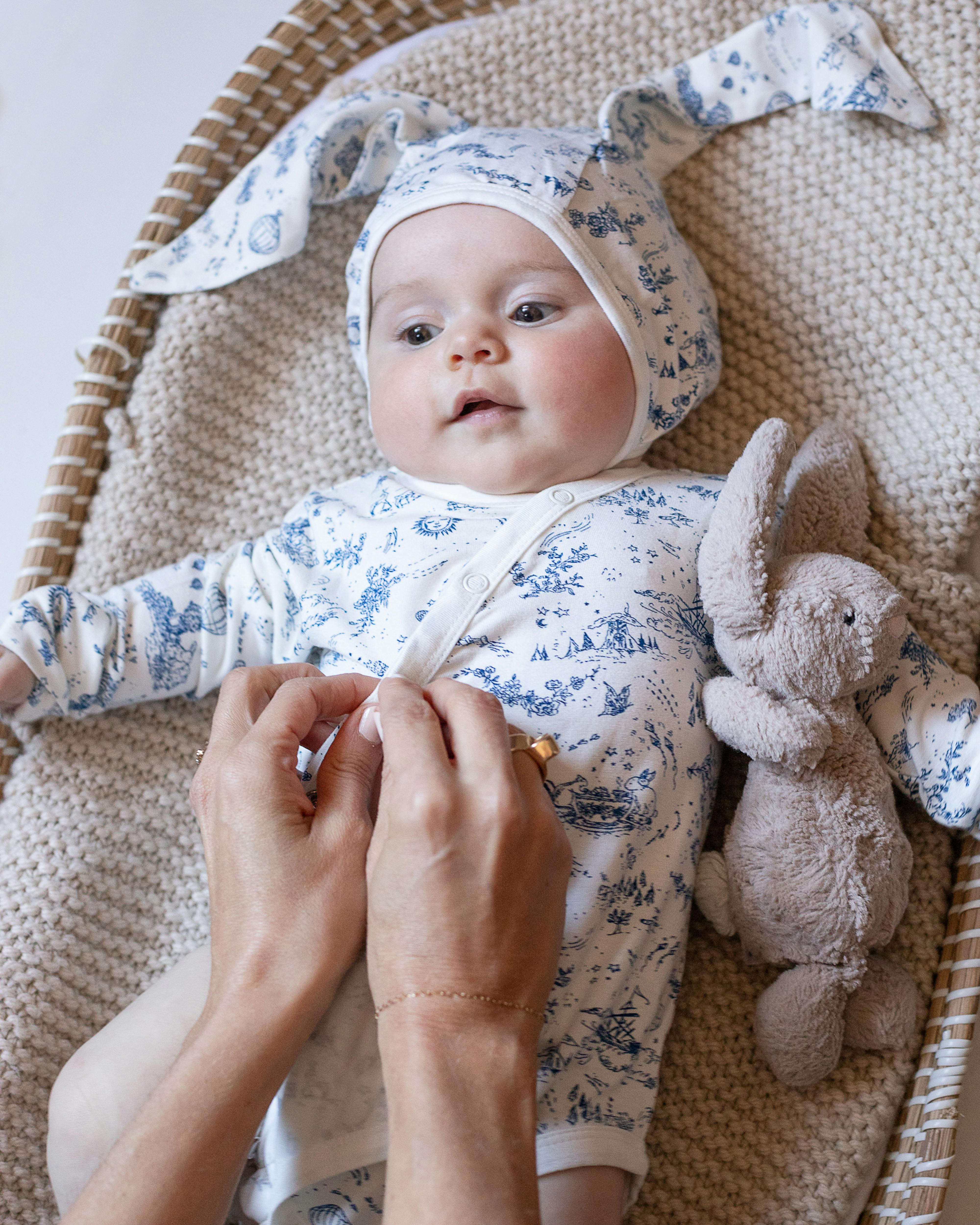 baby laying down and hands buttoning onesie