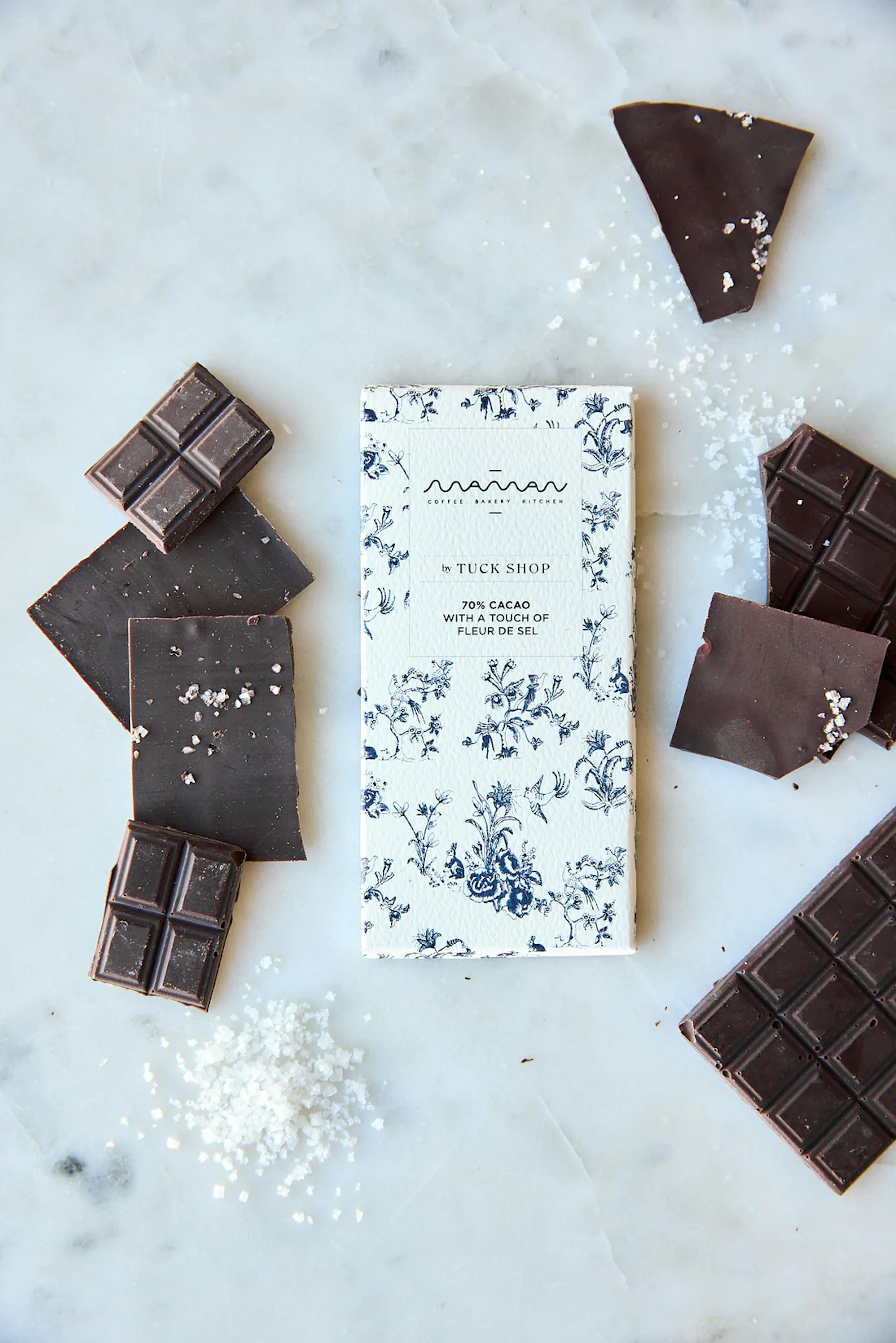 maman x tuck shop artisanal chocolate bar with blue floral packaging, featuring 70% cacao and a touch of fleur de sel, resting on marble tabletop