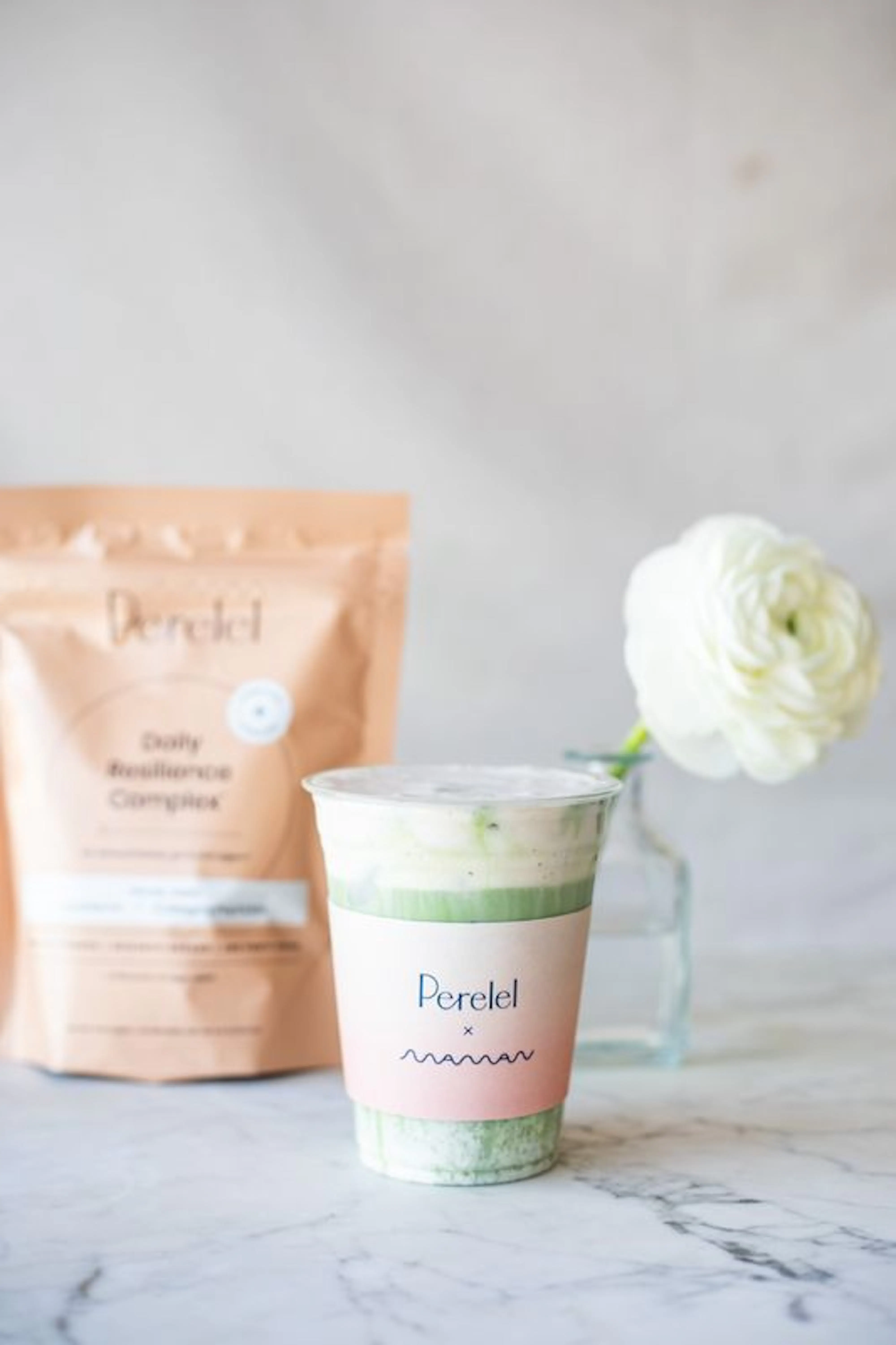 perelel to-go cup in front of a flower and perelel bag