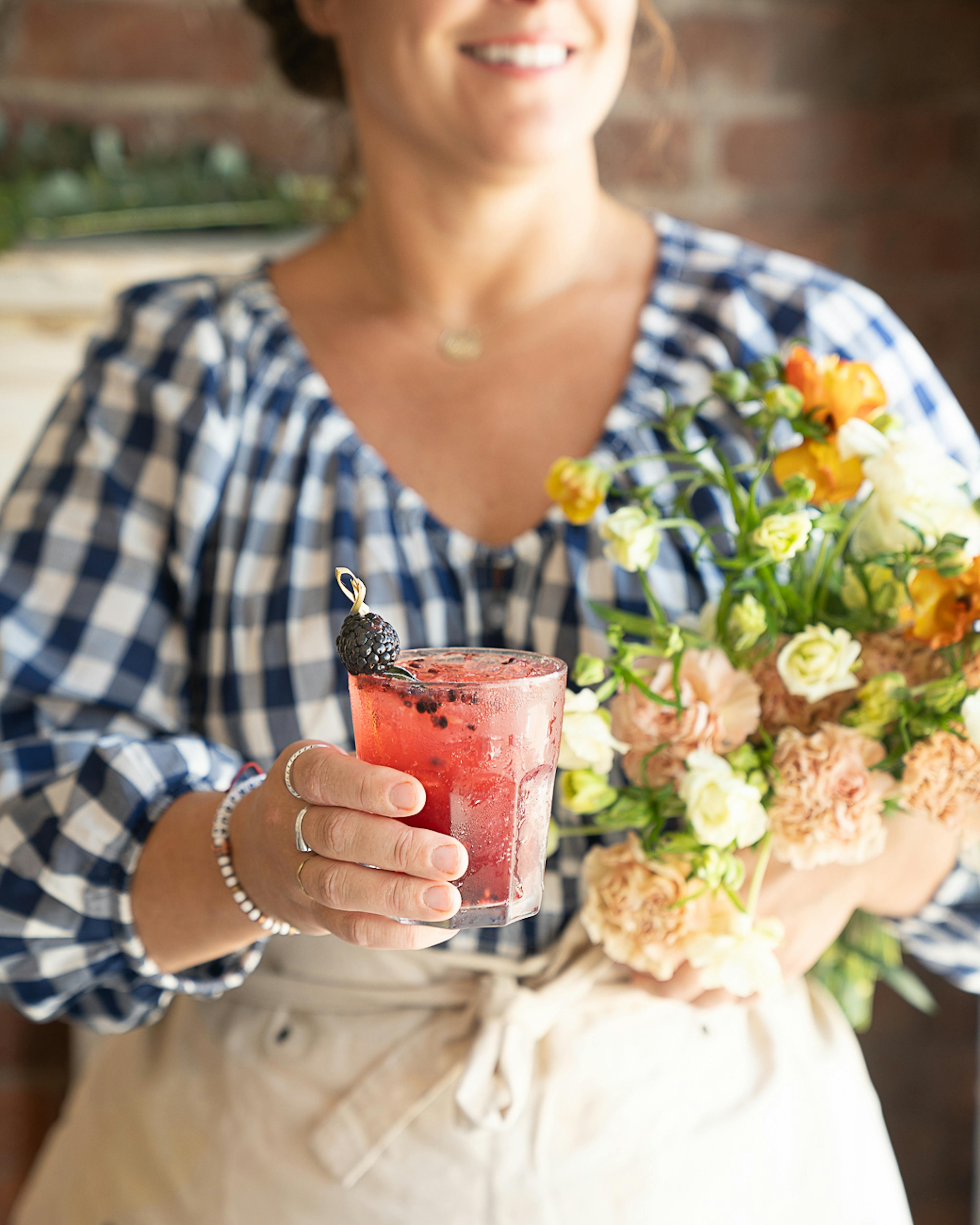 holding cocktail and flowers