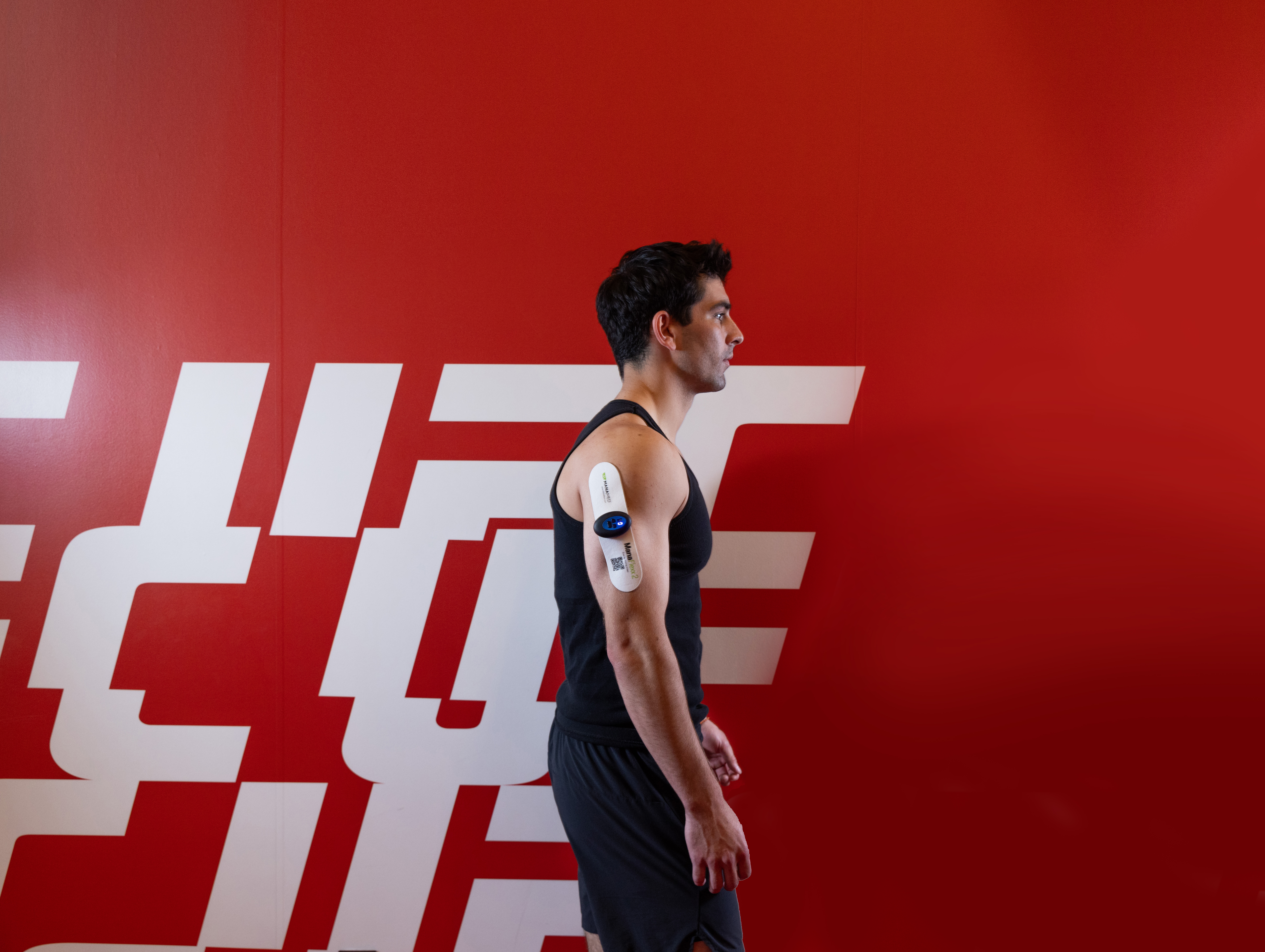 An athlete in front of the UFC wall wearing a ManaFlexx 2