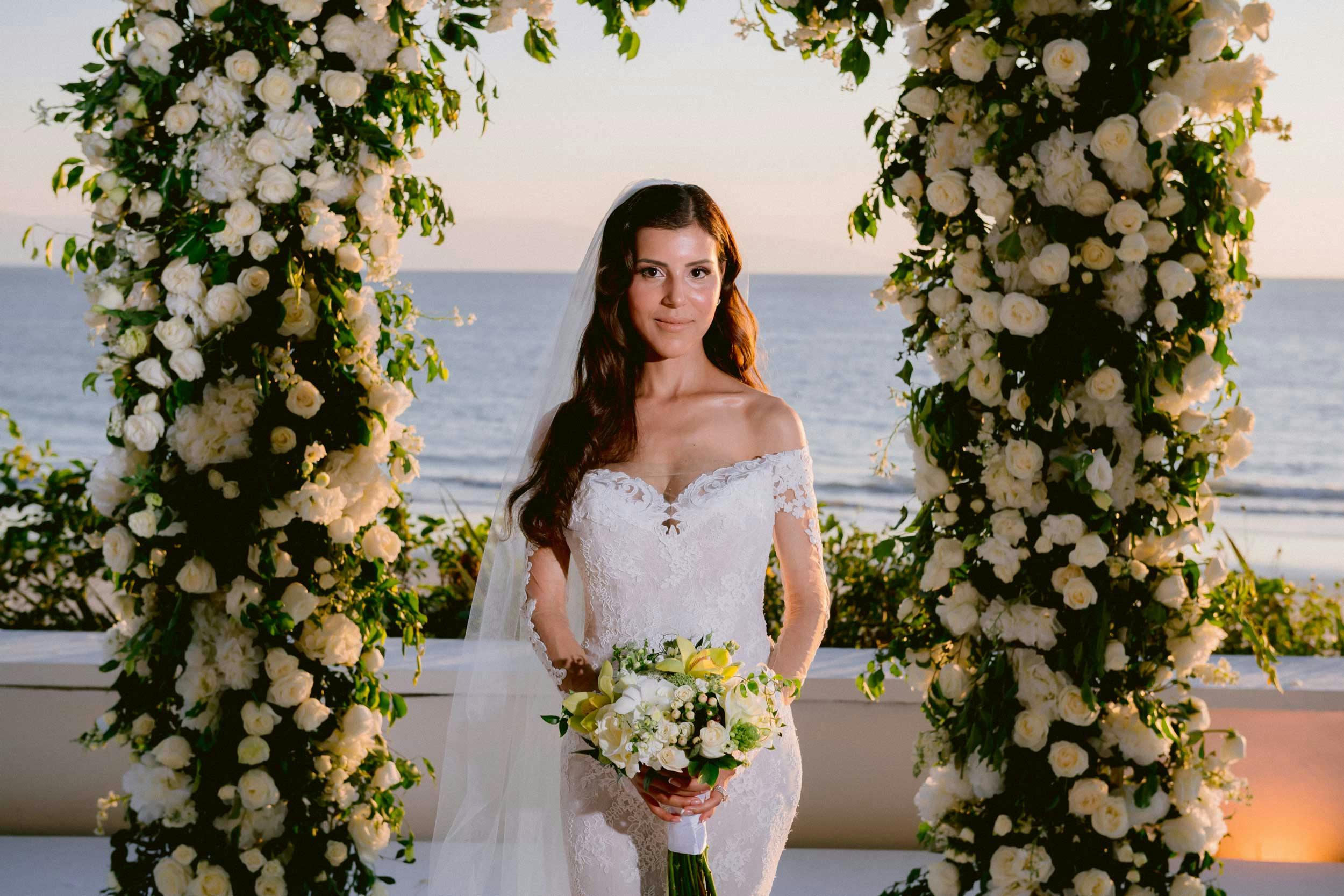 beautiful bride standing under flower arch