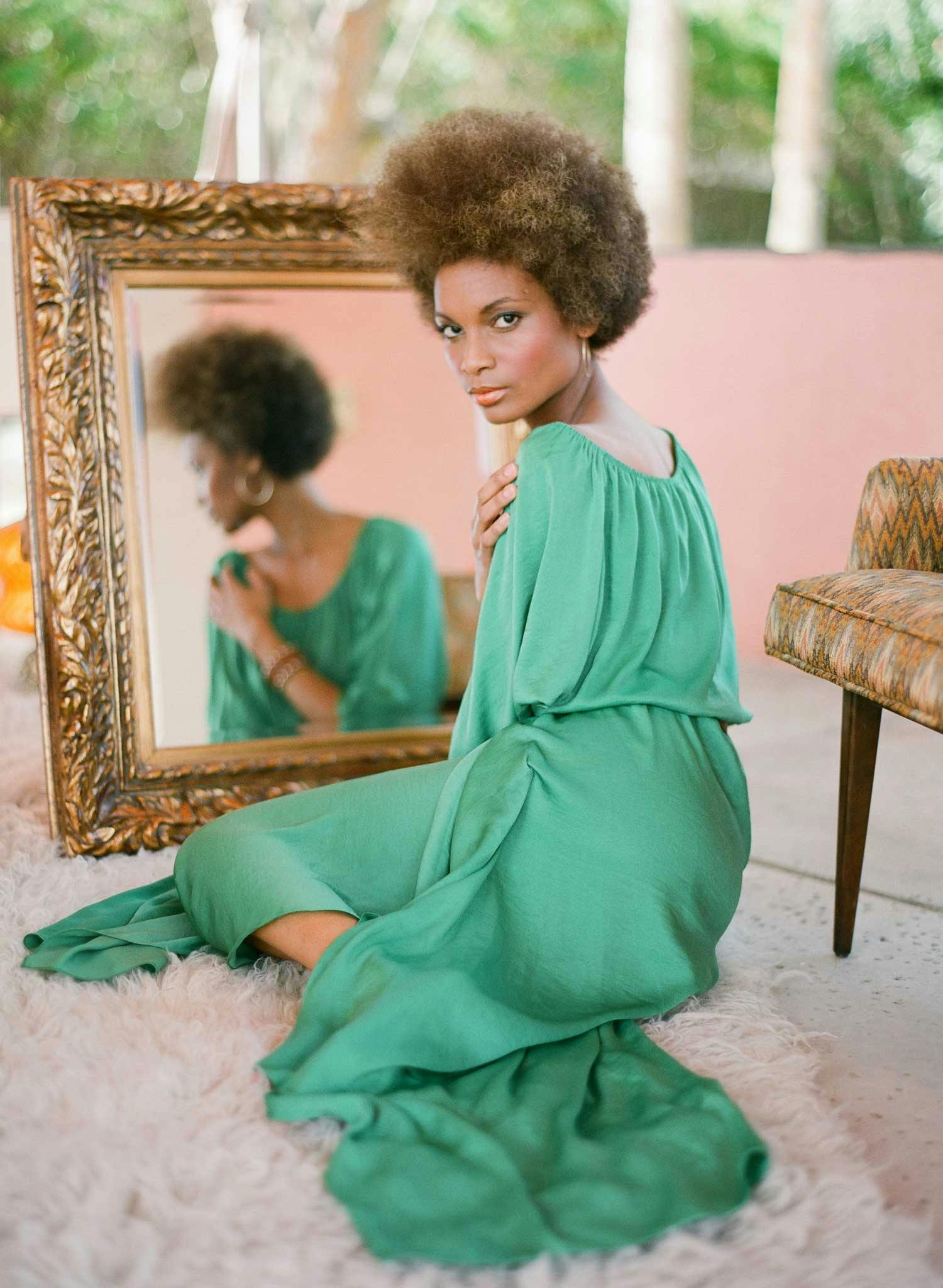 woman sitting on the floor in a green dress looking back at the camera