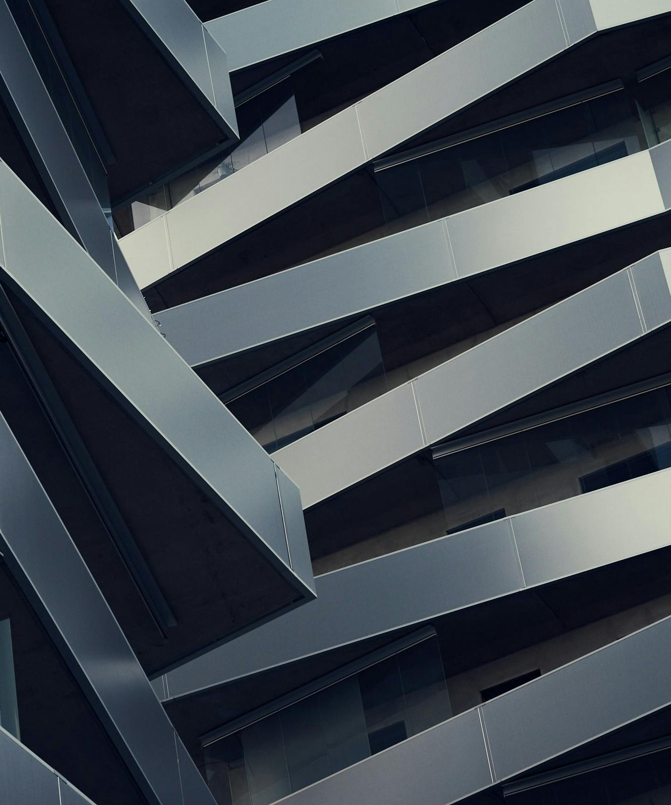 An abstract view of a modern building's facade featuring overlapping metallic panels and angular designs.