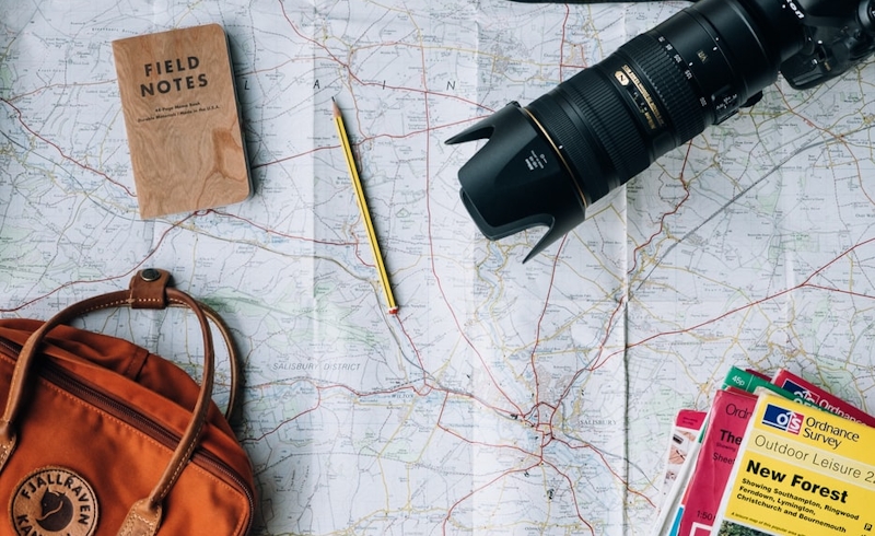 Travel must-have attributes: note, camera, bag, and brochures, placed on the map