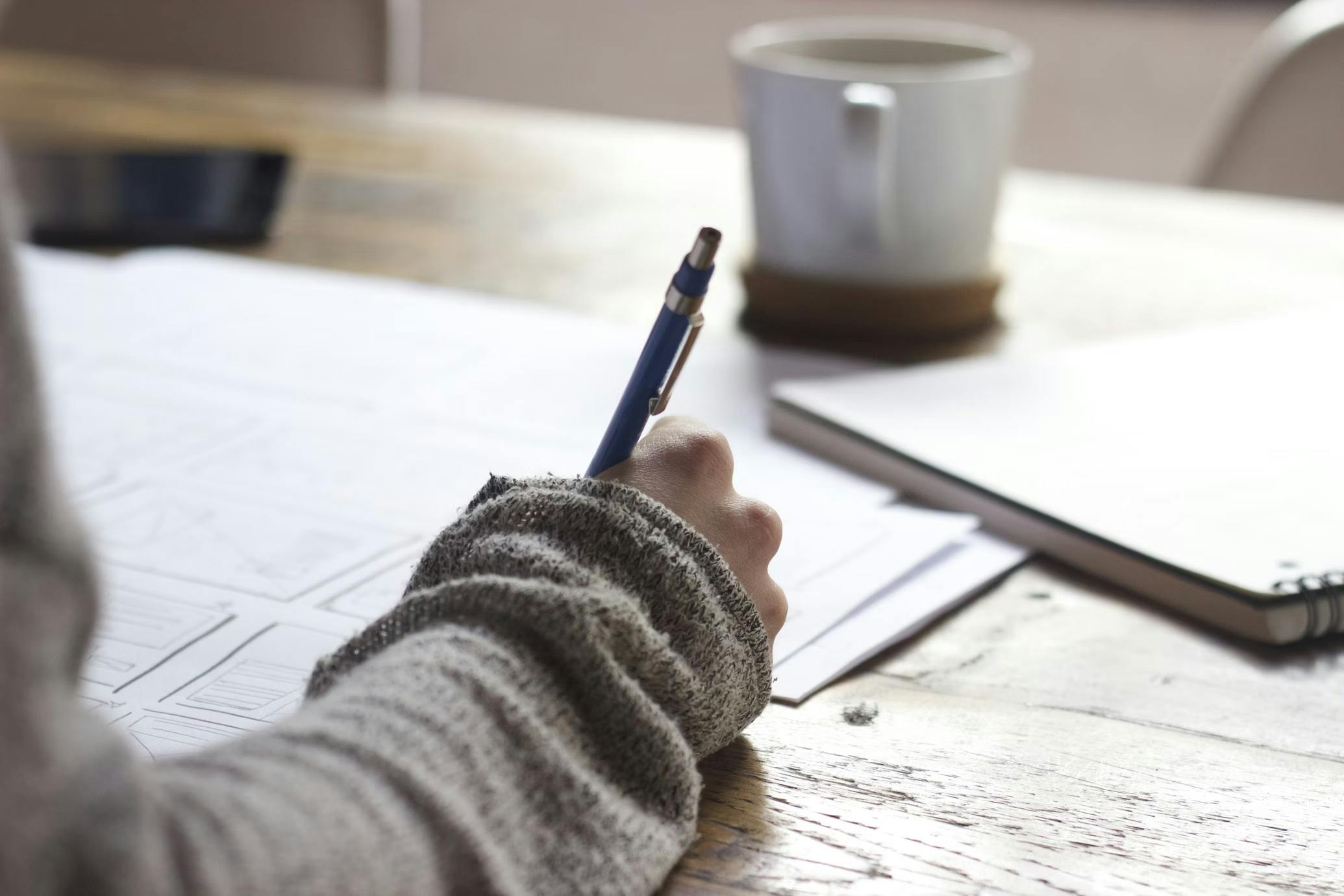 Image of hand with pen over a paper