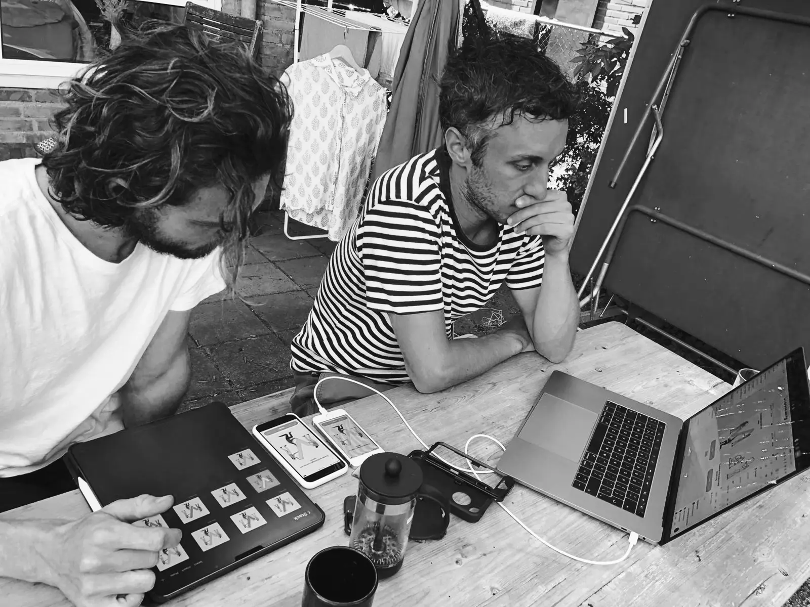 Sjoerd and Martijn are sitting next to each other. Sjoerd has a tablet used for drawing in front of him with a range of illustrations visible on screen. Martijn has a laptop in front of him showing interfaces with illustrations in them.