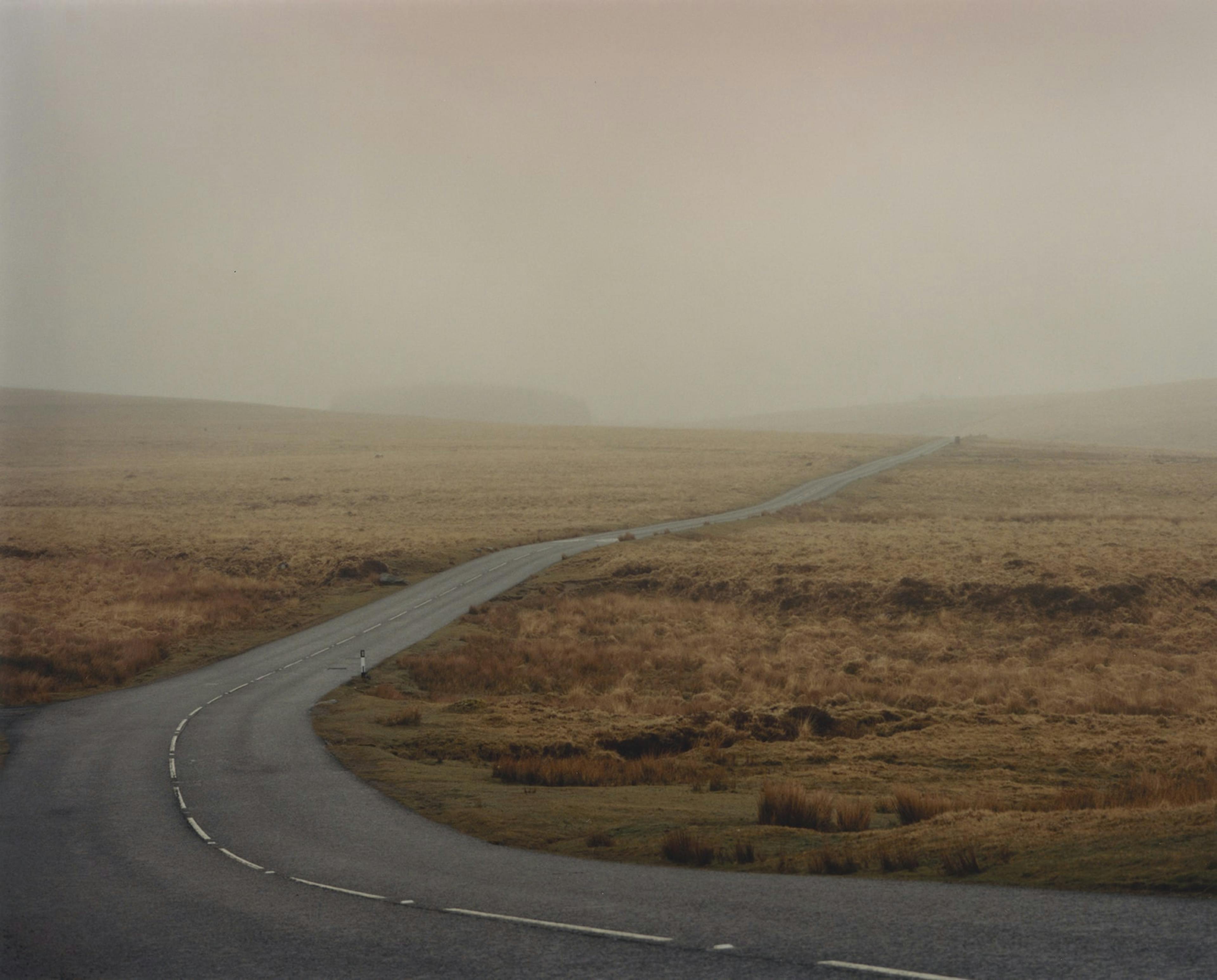 an empty country road crossing a field