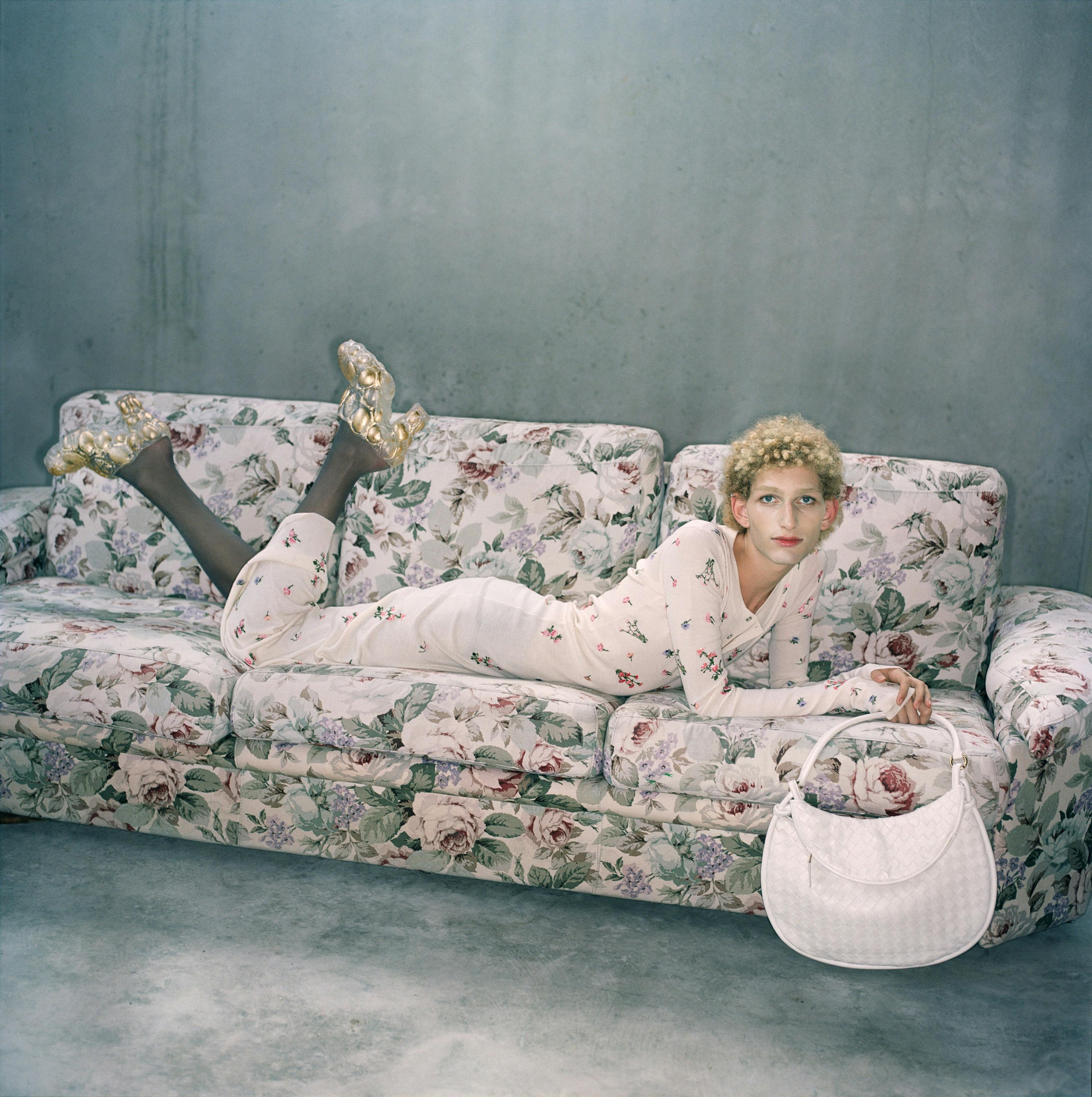 blonde person laying on a patterned sofa