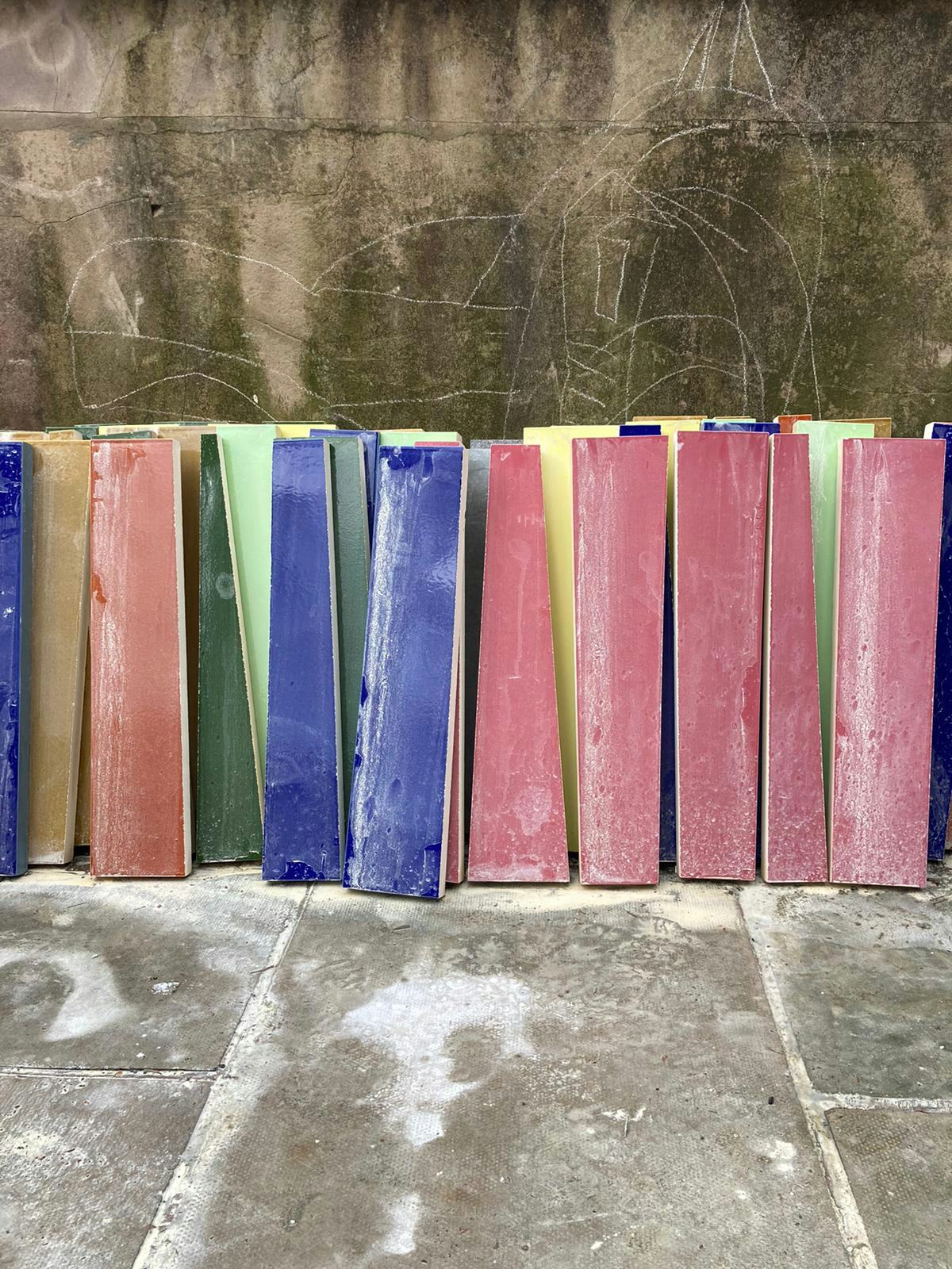 A row of large, colourful tiles stacked against a wall