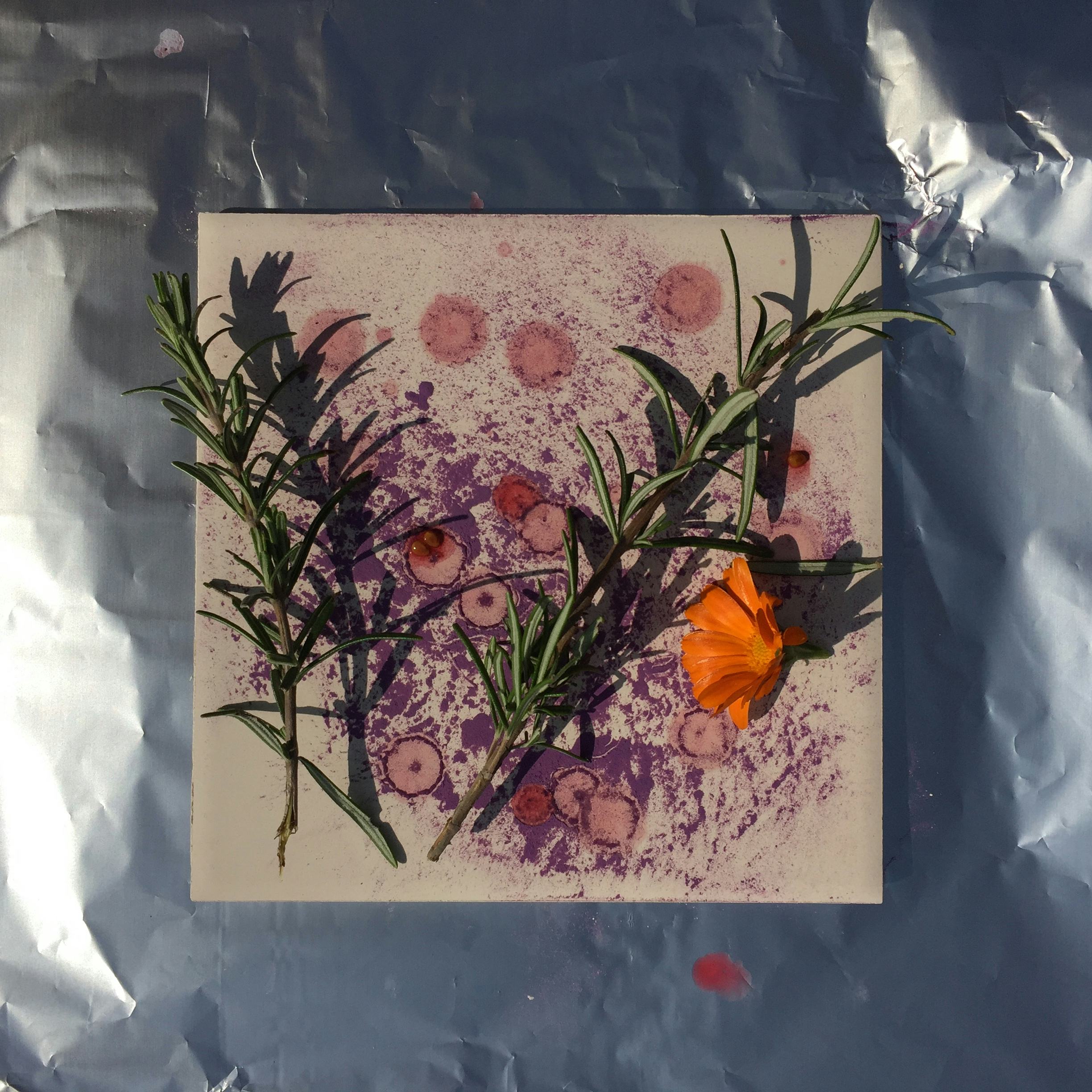 Flower and plant cuttings on top of a clay tile that sits on top of metal foil