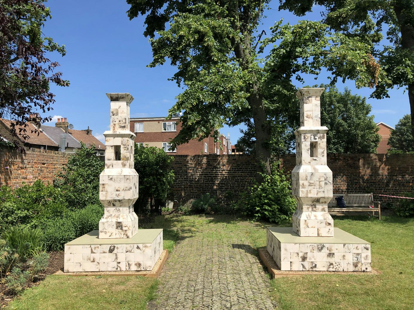 Two ceramic tiled lanterns in a walled garden