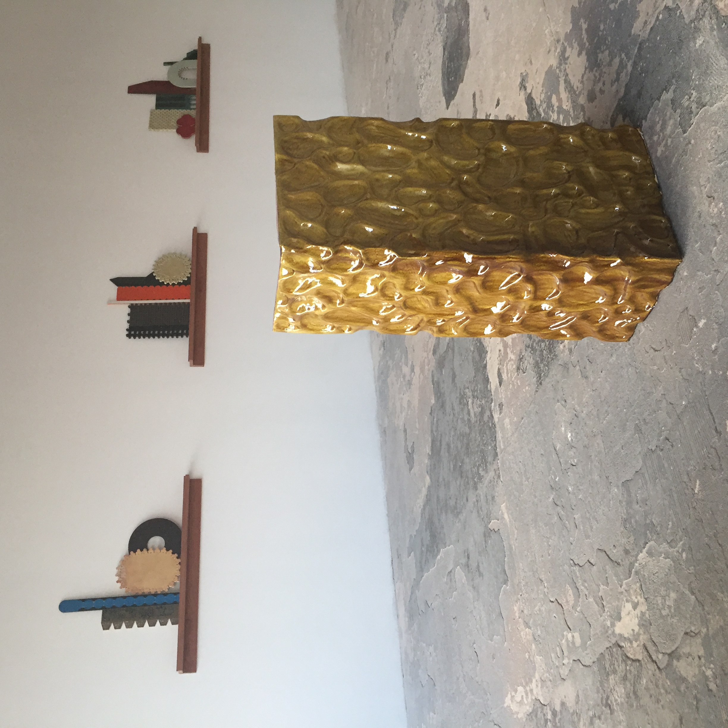 An art gallery with ceramic artworks on the wall and floor