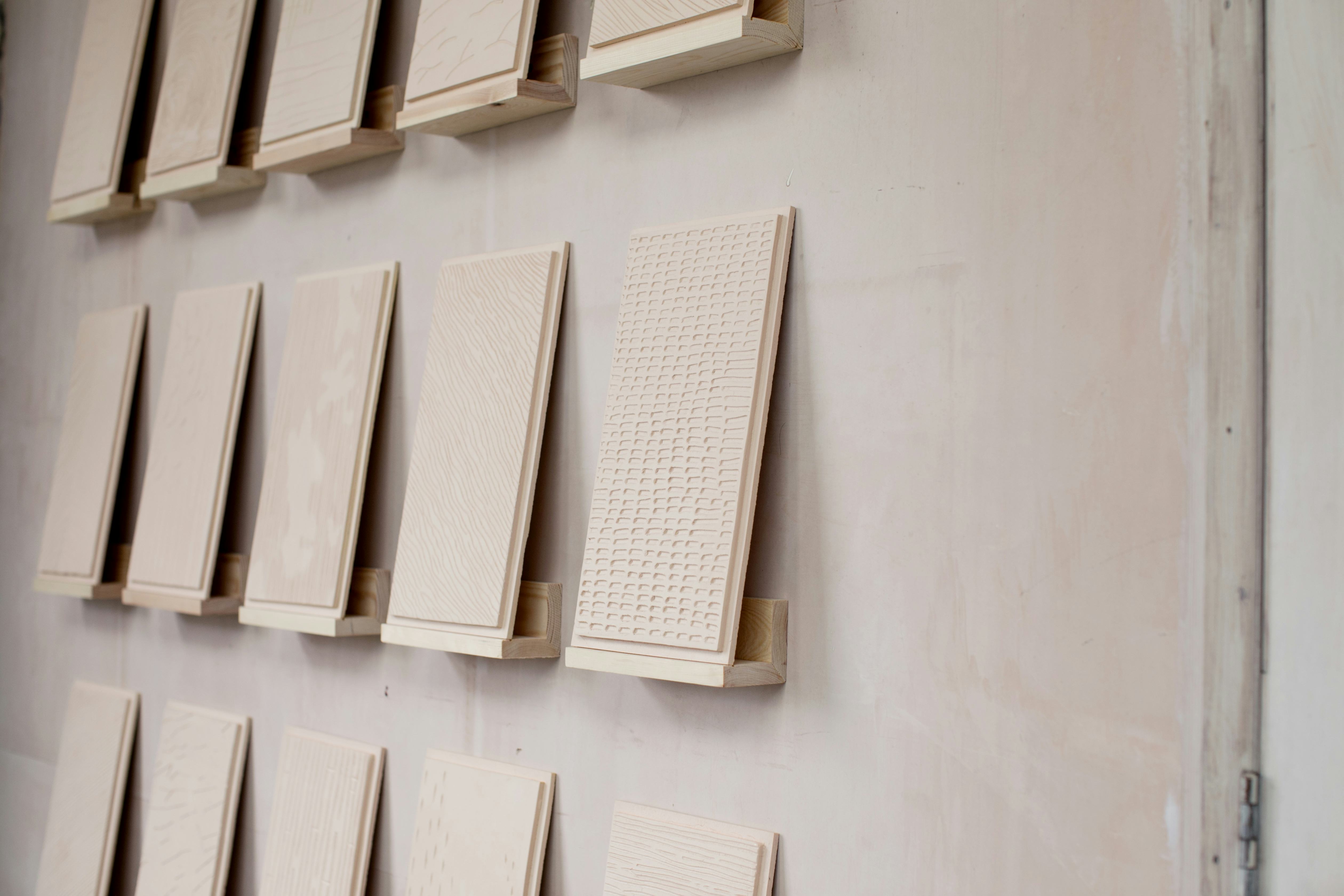 Clay tiles with handmade markings sit on individual wall shelves