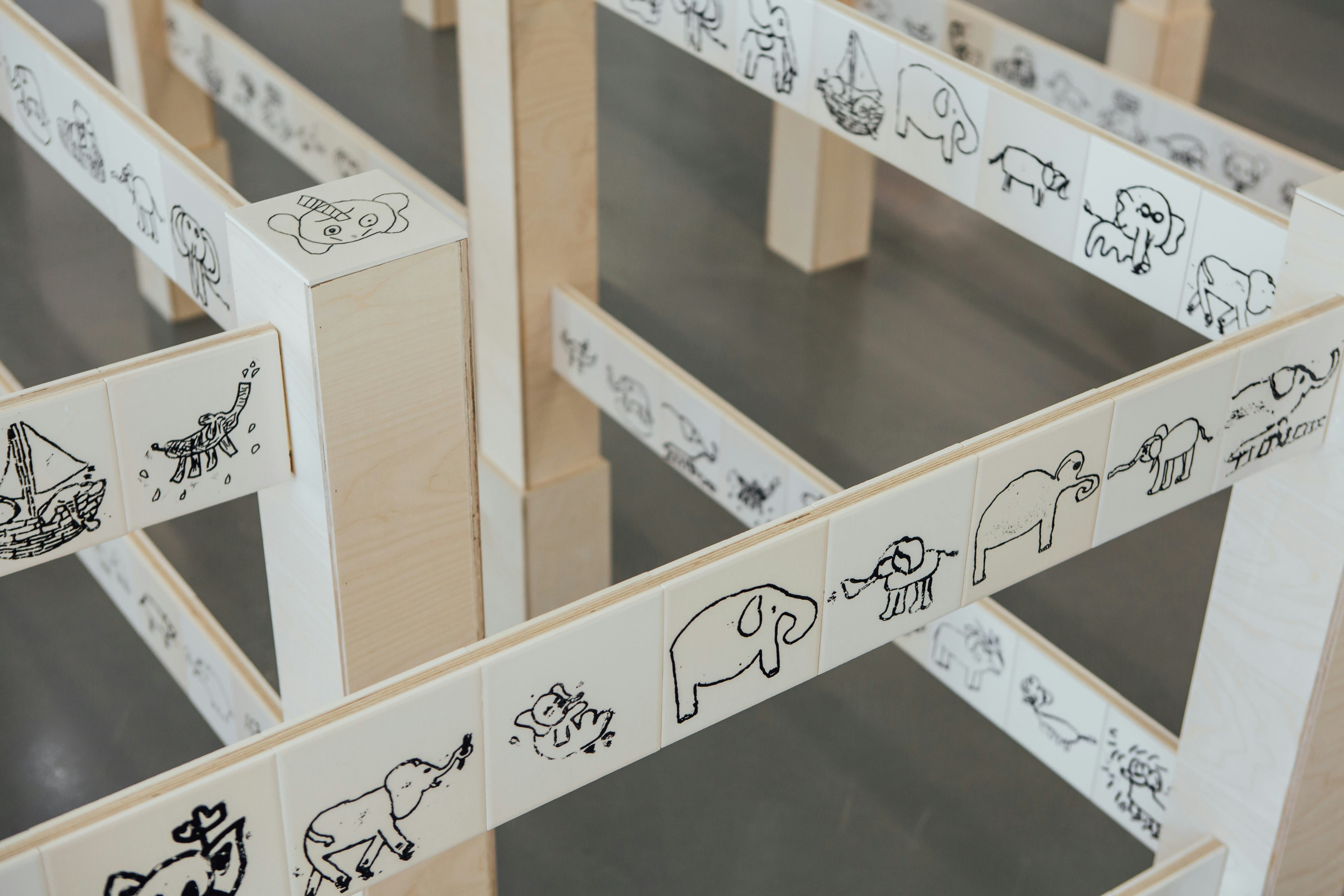 A detail of an art installation with ceramic tiles covered in childrens’ drawings of an elephant