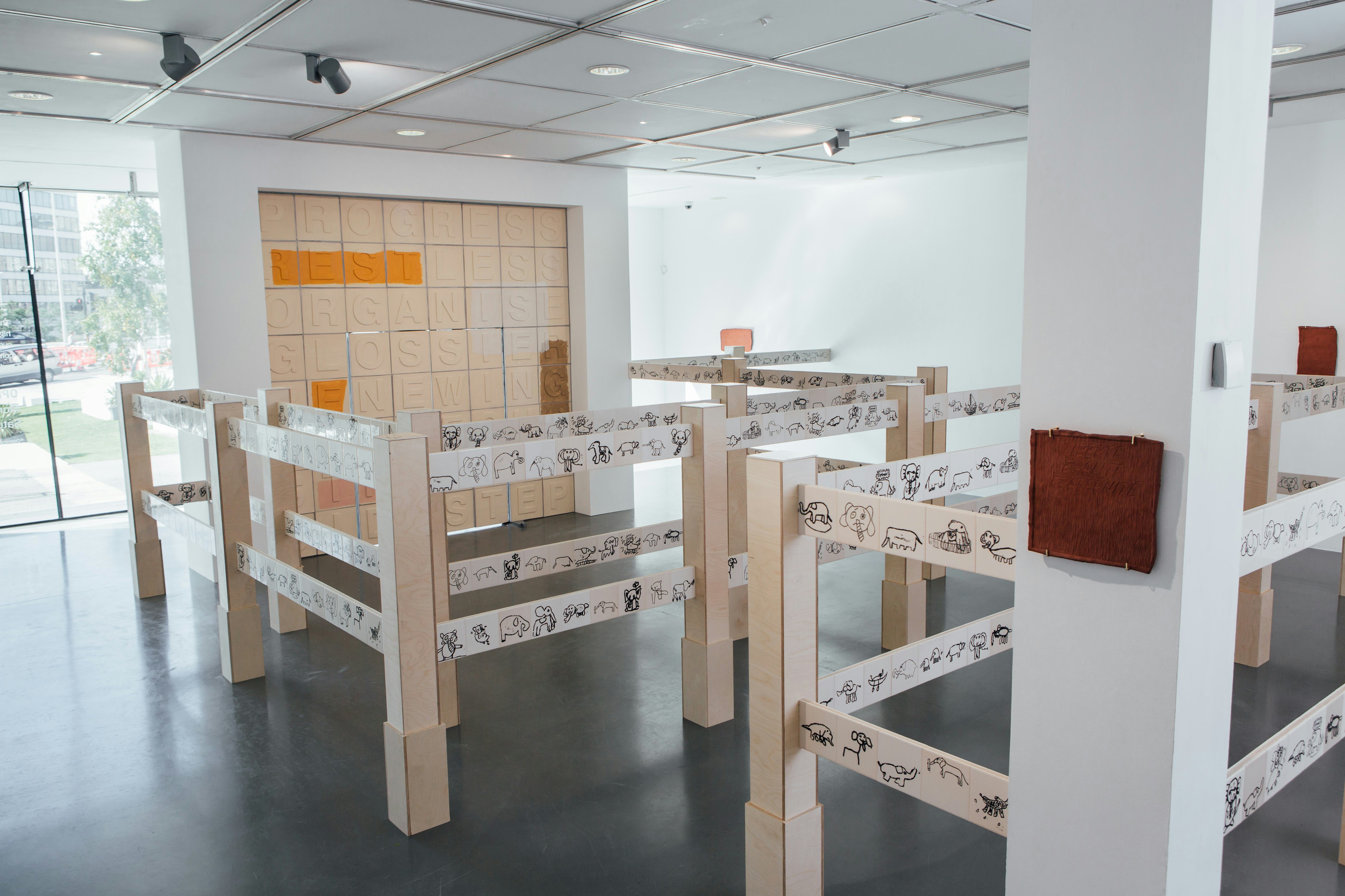 An art gallery with a large ceramic installation and smaller ceramic pieces on the walls