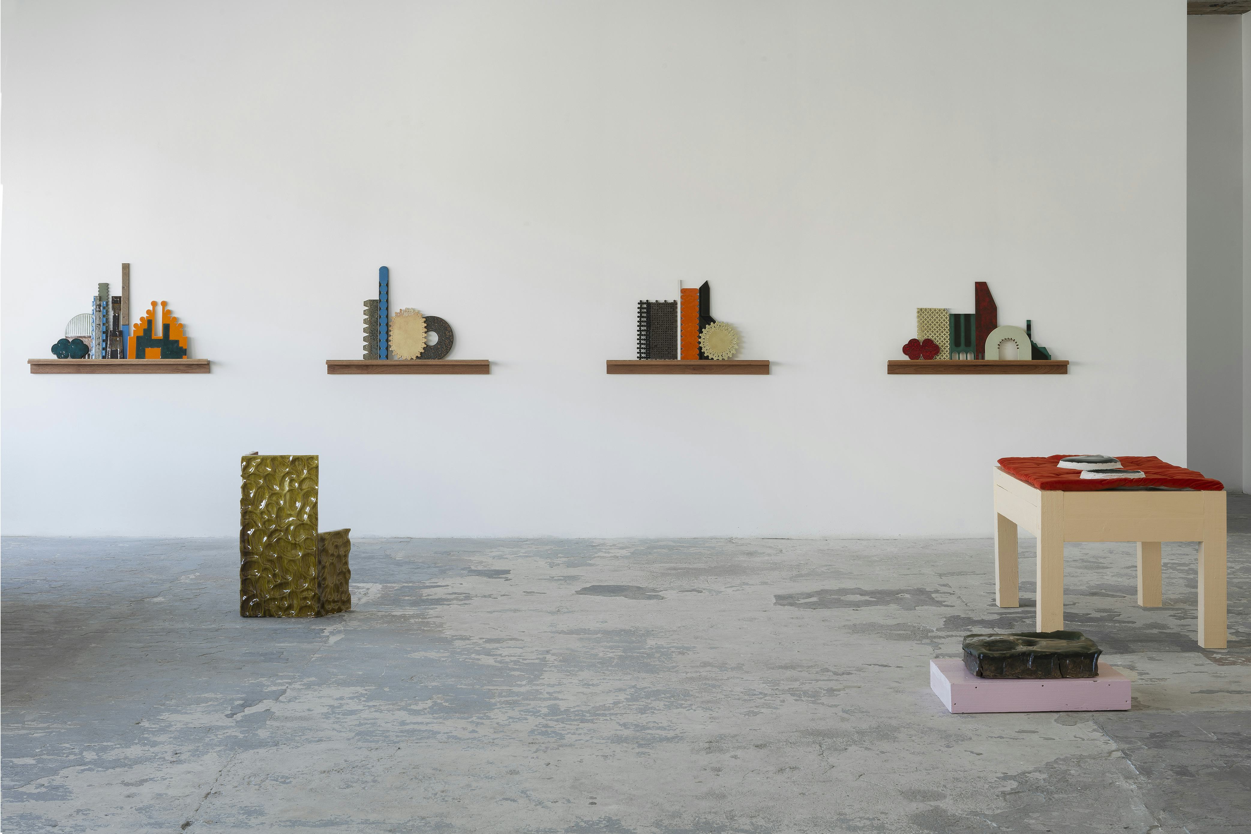An art gallery with ceramic artworks on the wall and floor