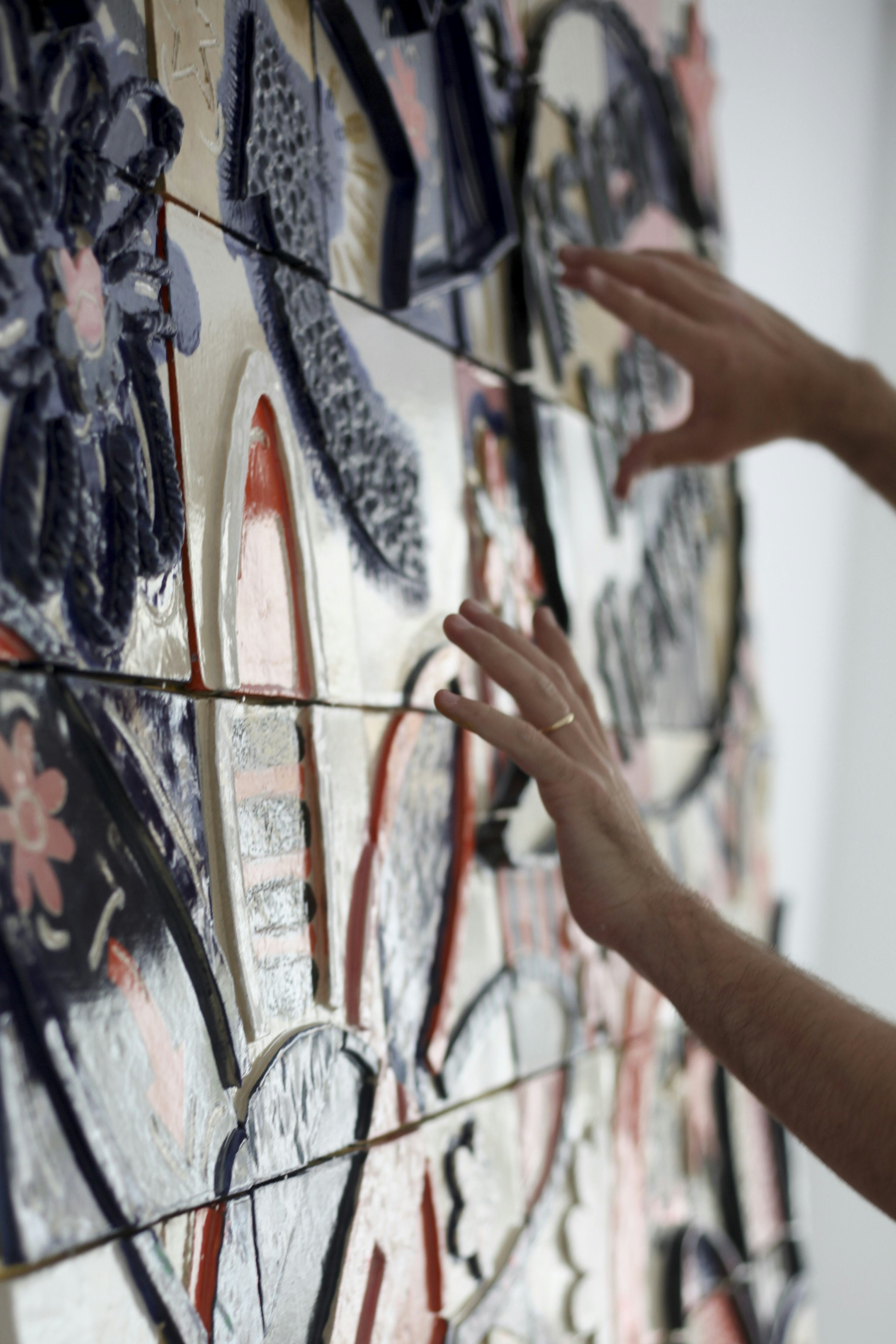 Hands touching a tiled mural