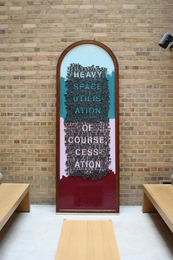An artwork leans against a wall. The words ‘heavy space utilisation of course cessation’ are displayed on the artwork