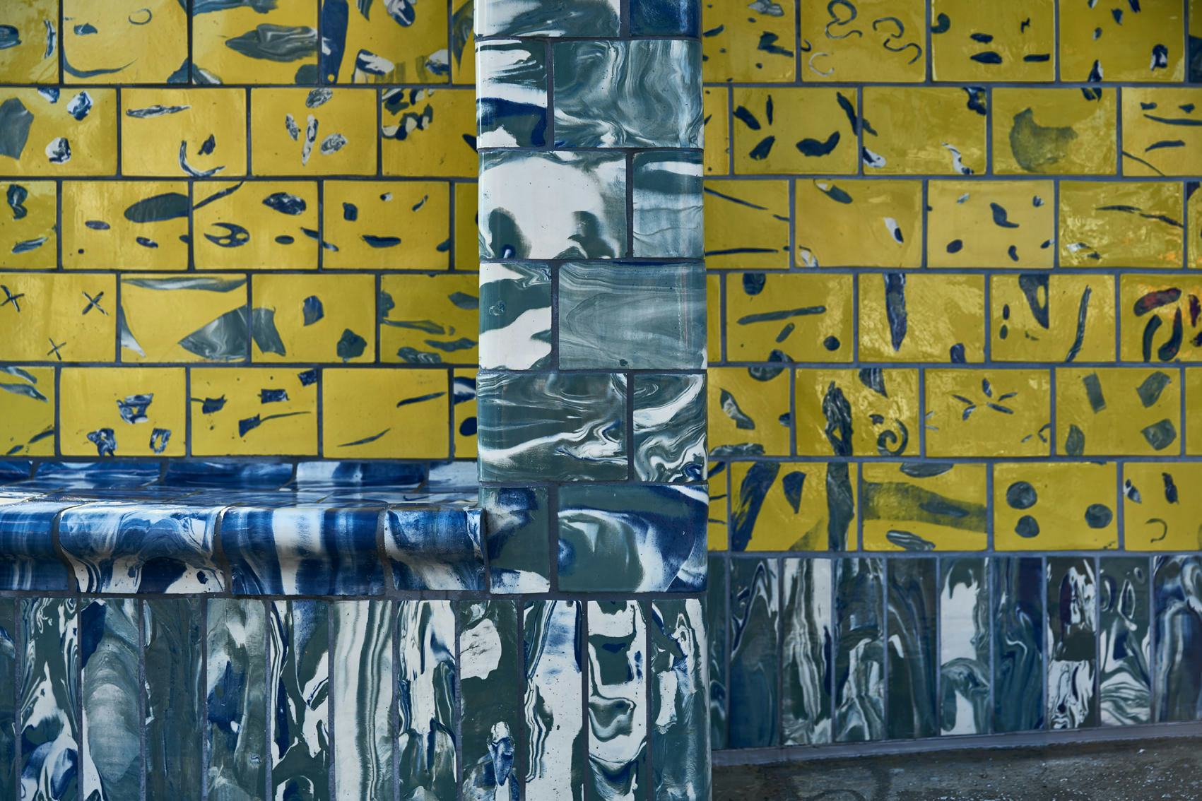 A detail showing handmade yellow and blue tiles on a transport kiosk